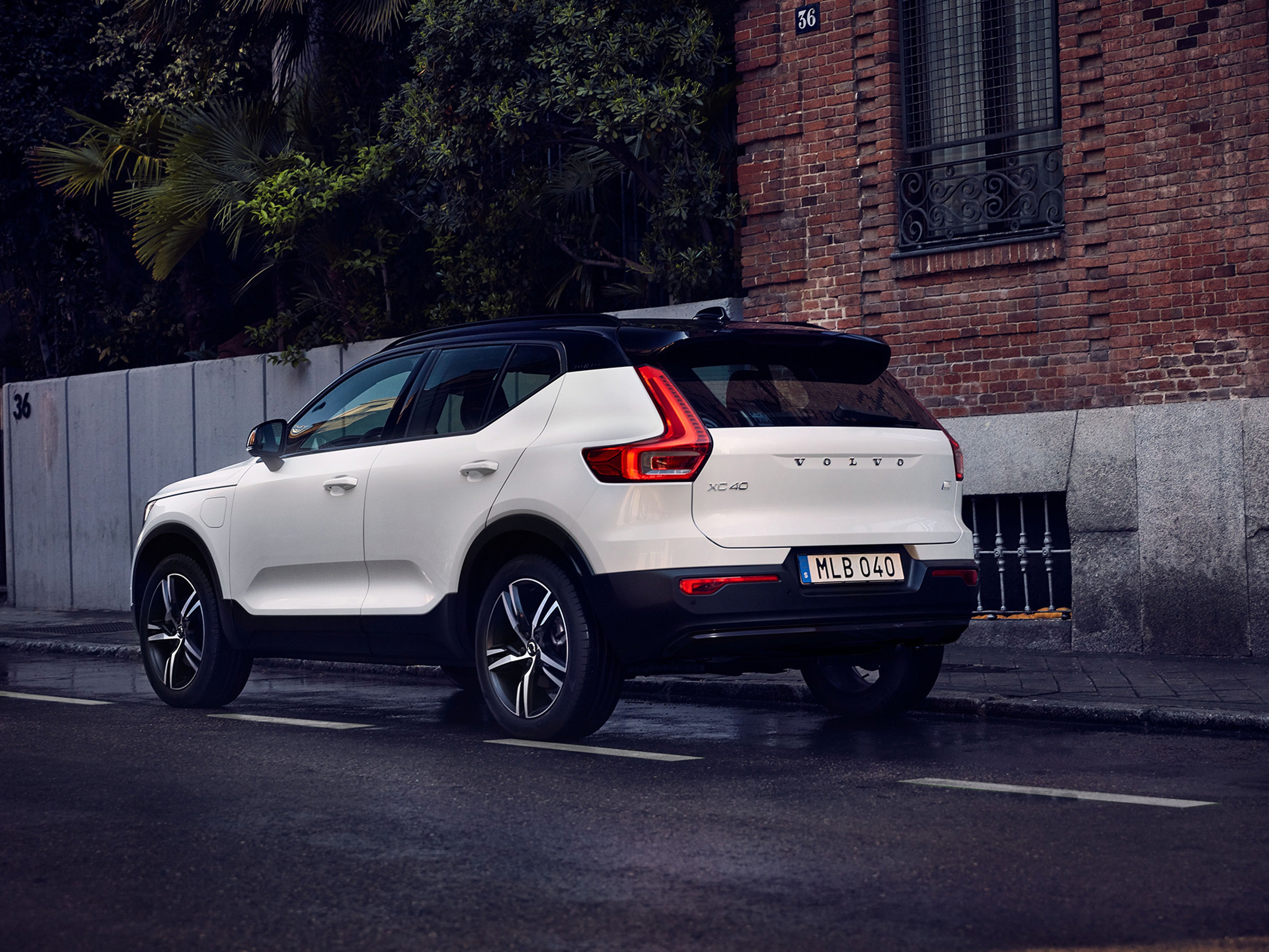 XC40 branco vista traseira numa estrada, com uma parede de pedra