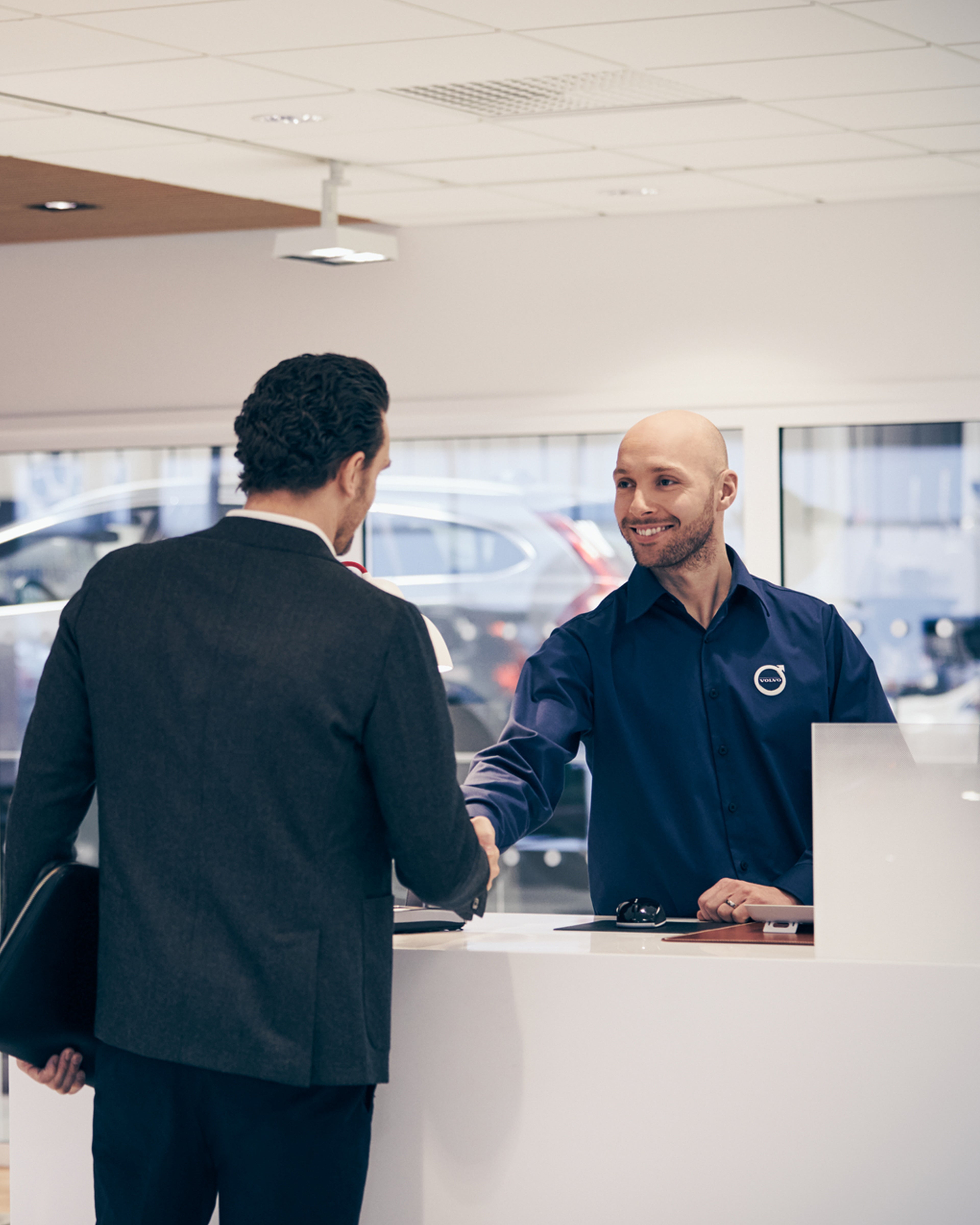 Kunde i dress som håndhilser en Volvoansatt