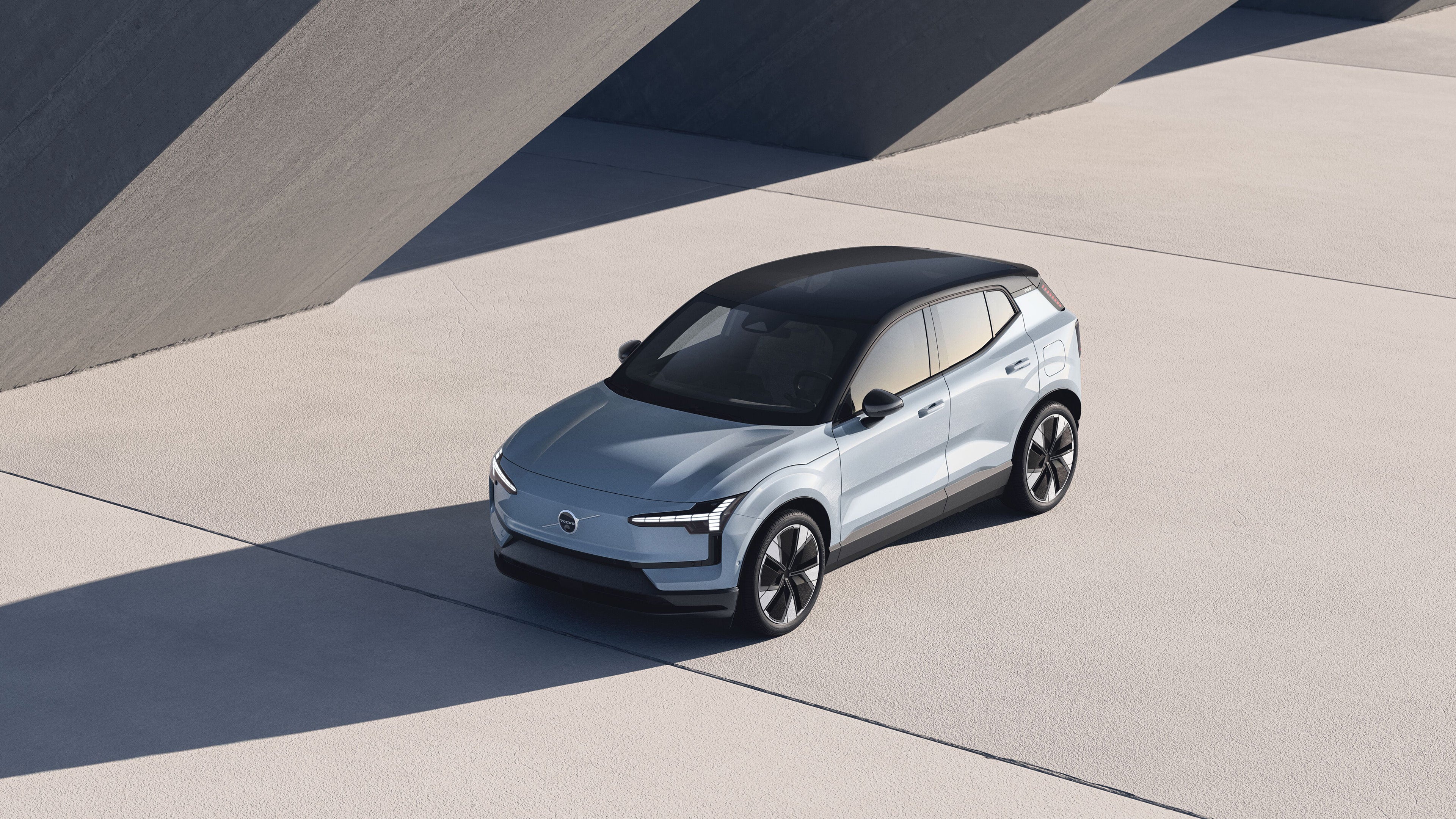 An aerial image of the front and side view of the fully electric cloud blue Volvo EX30 SUV.