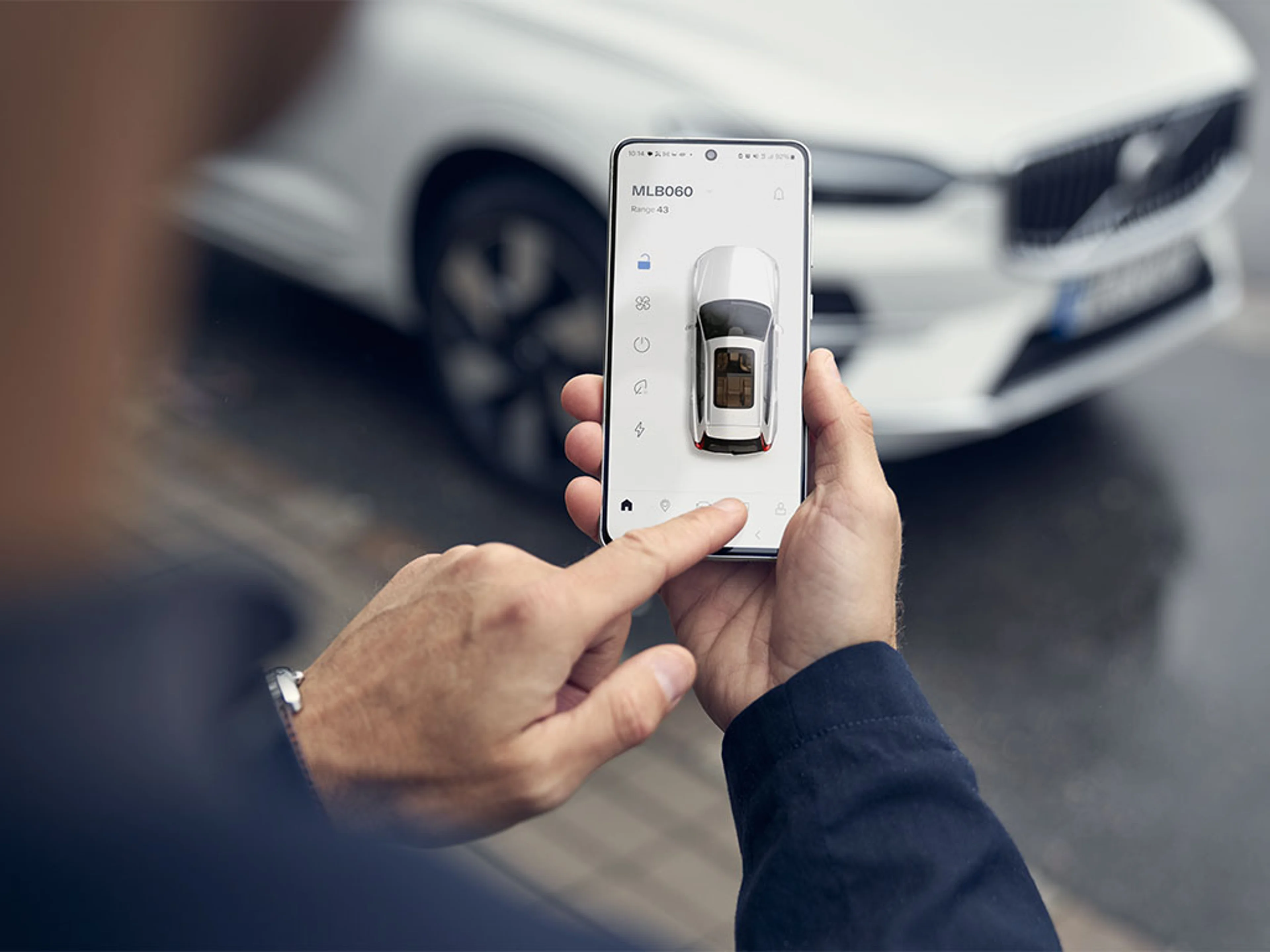 Personne utilisant l'application Volvo Cars reliée à une Volvo blanche en arrière-plan