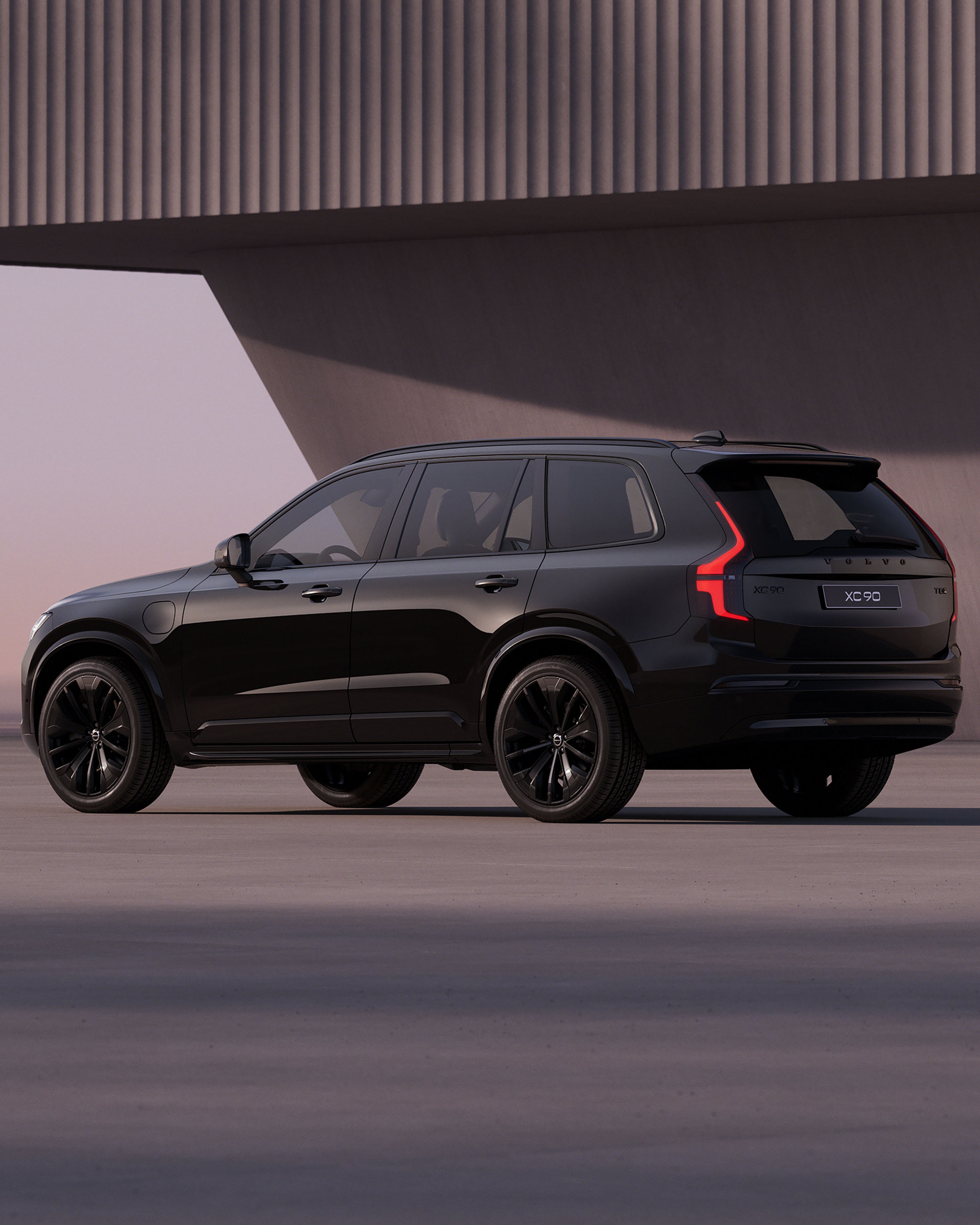Seitenansicht eines schwarzen Volvo XC90 vor einer hellen Steinwand in lilanem Sonnenuntergang Panorama.