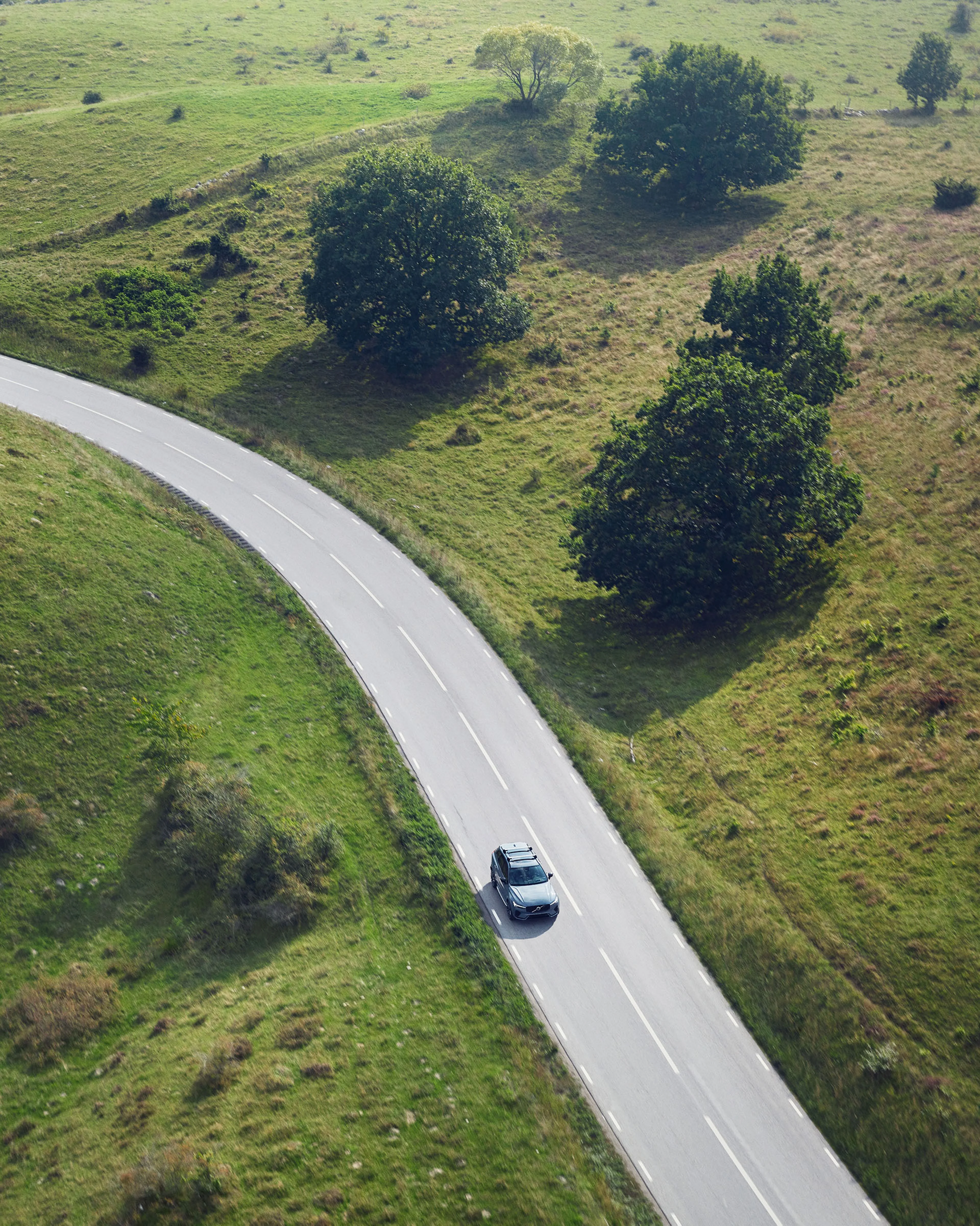 Volvo rijdend door een mooi groen landschap.