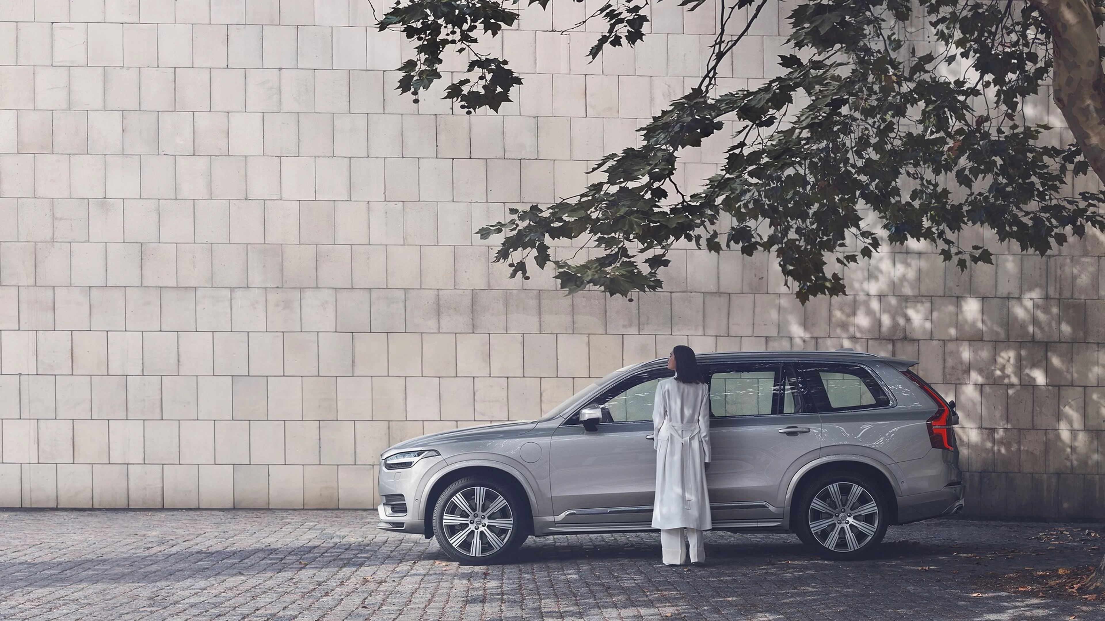 Egy nő áll egy szürke Volvo előtt