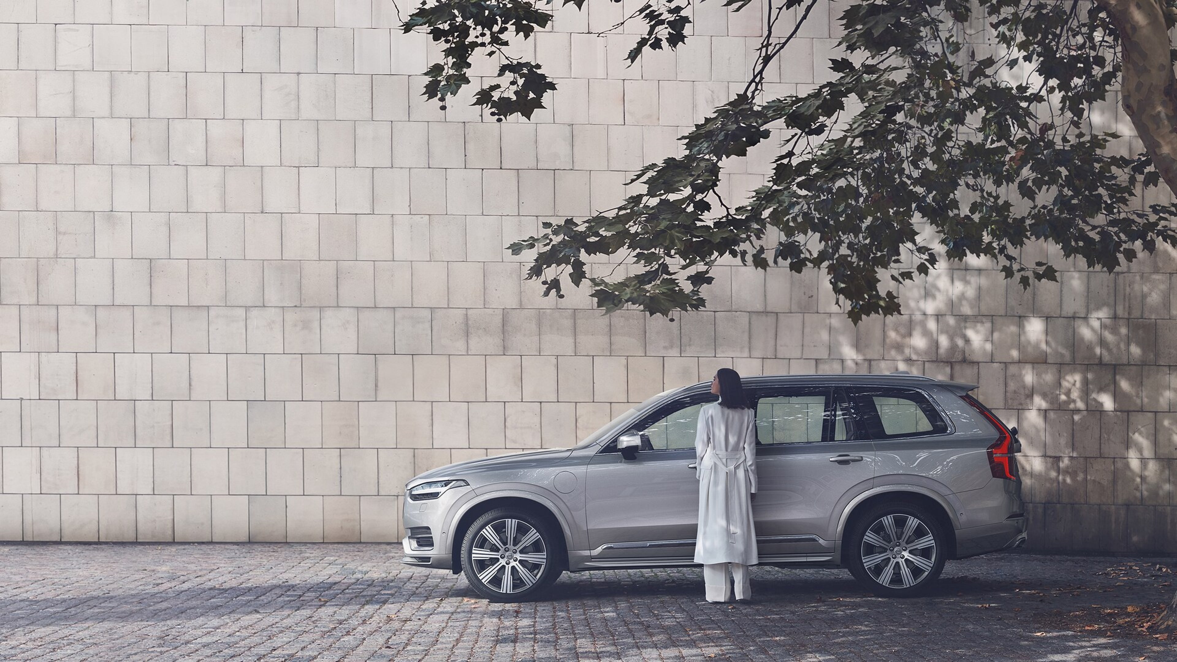 Egy nő áll egy szürke Volvo előtt