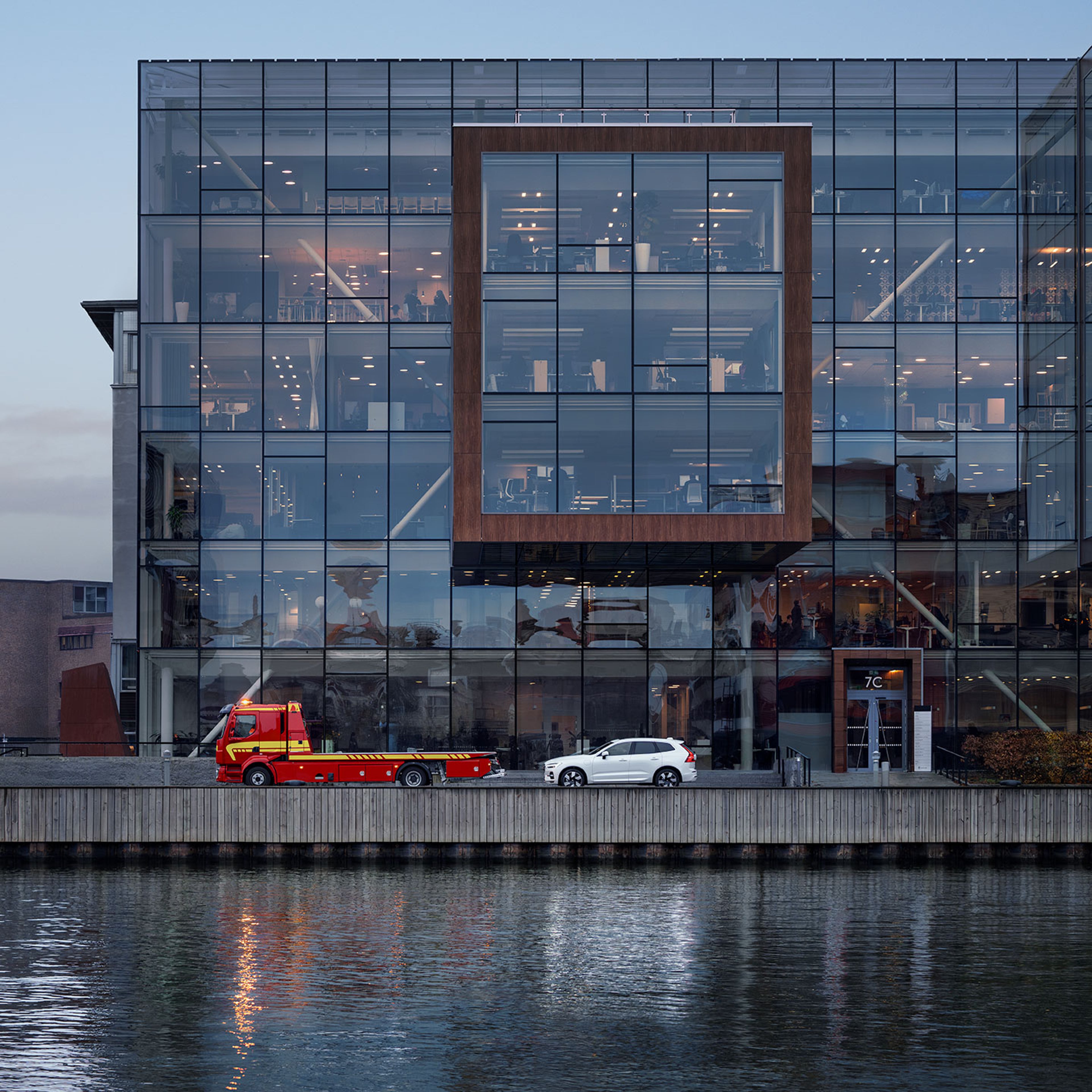 En bil fra Volvo bliver hentet af vejhjælp, set længere væk fra siden i et kontormiljø på havnen.