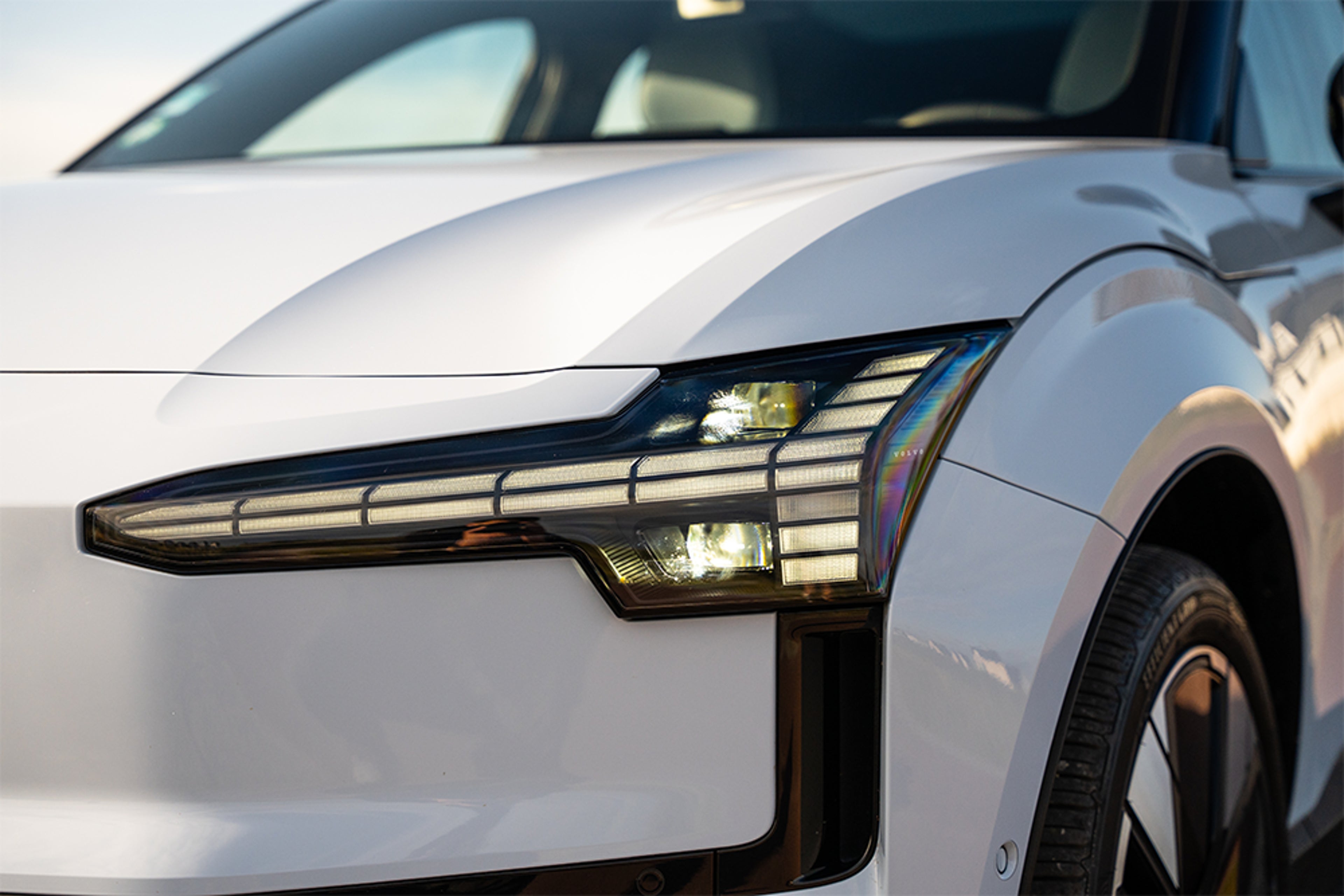 Gros plan sur phare avant d’une Volvo blanche au design moderne et lignes nettes.