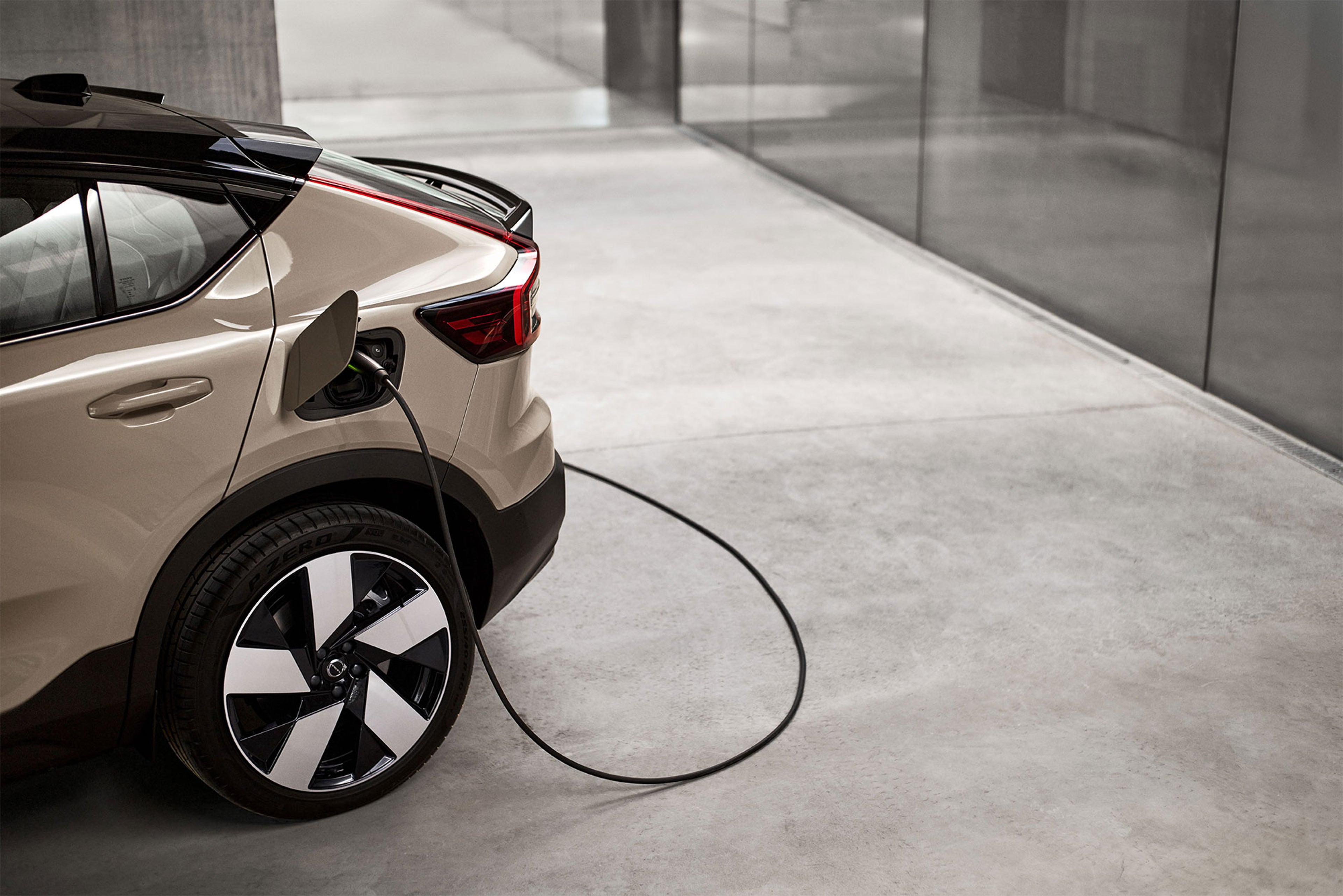 Arrière d’une Volvo EC40 branché à une borne de recharge dans un espace moderne en béton et verre