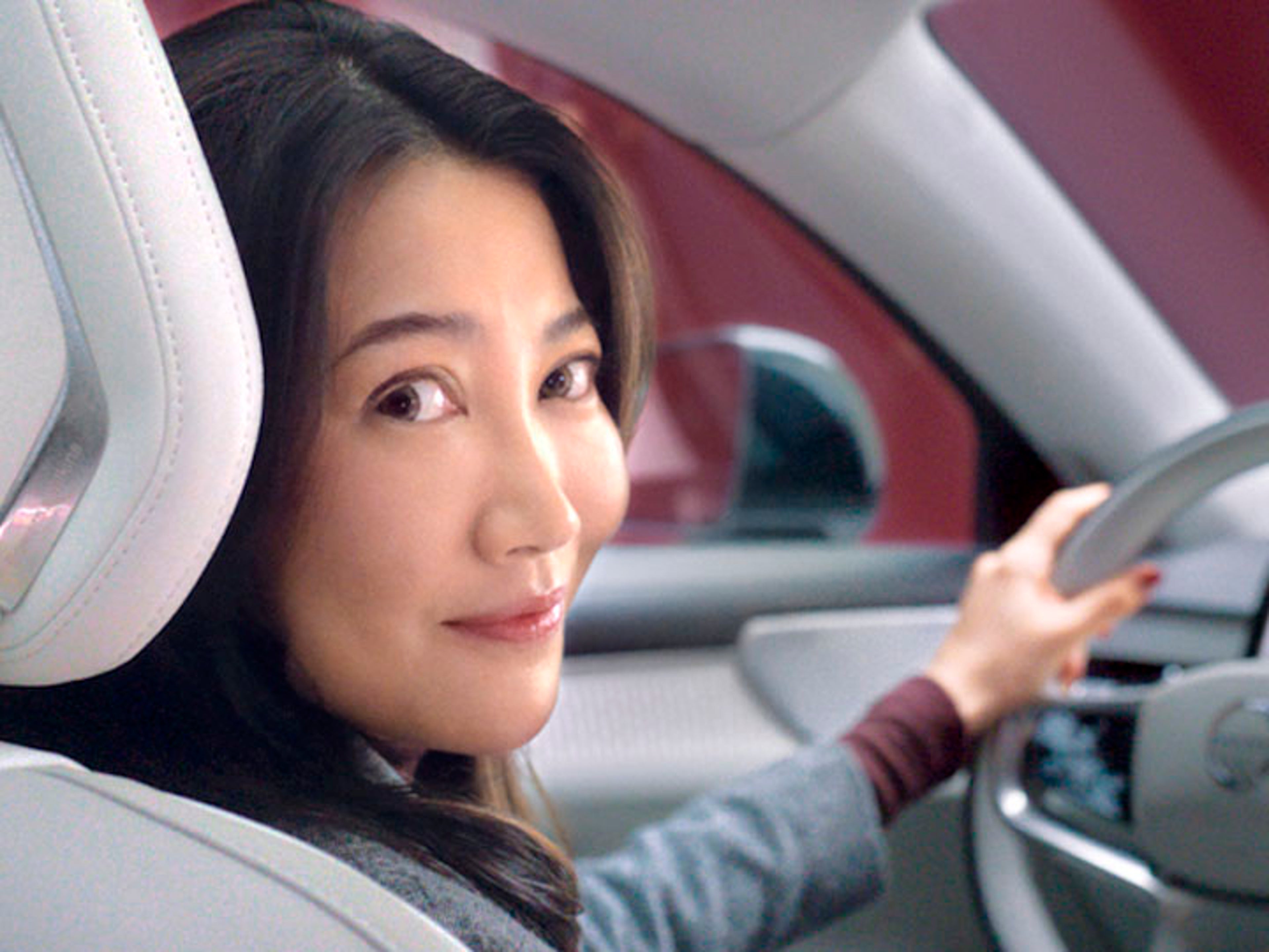 Una mujer al volante de un Volvo mirando a cámara