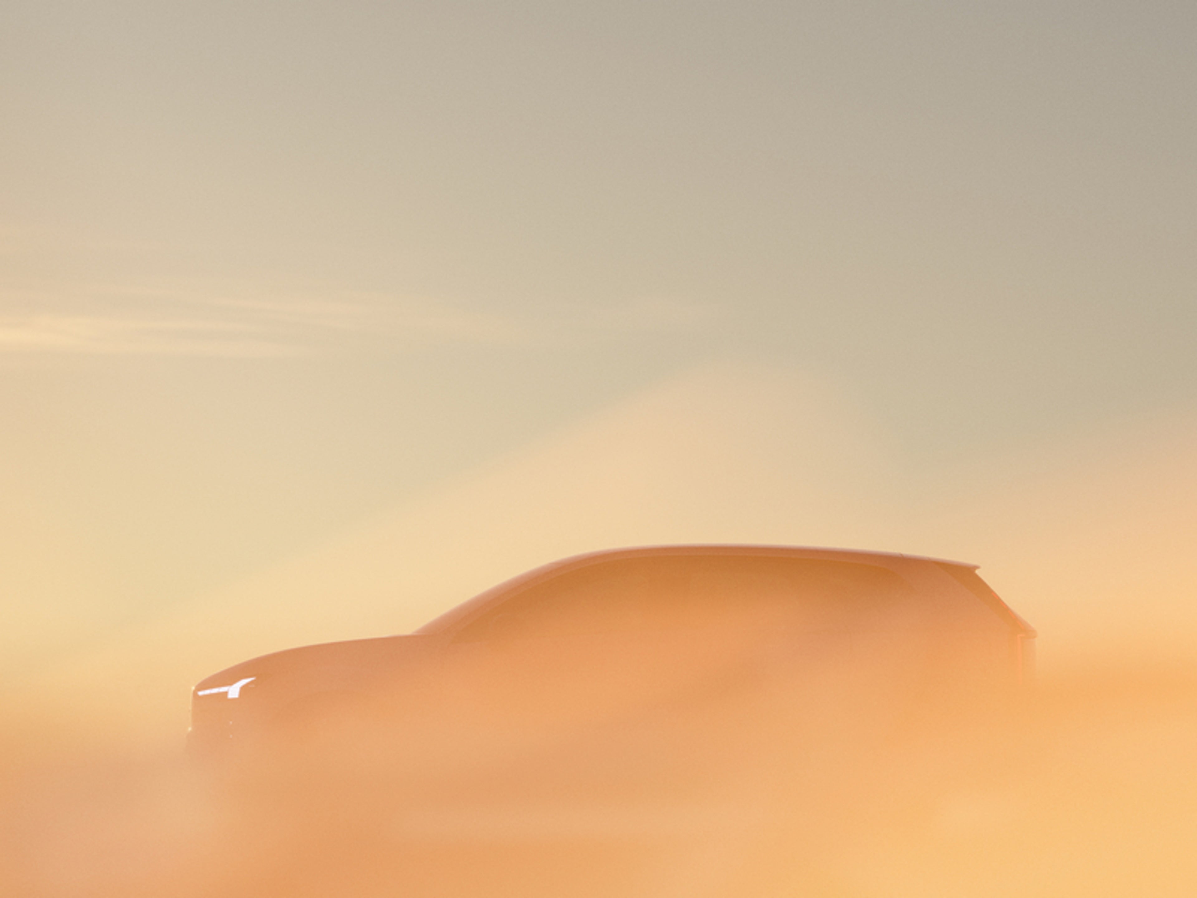 Silhuet af en bil med oplyste forlygter, delvist skjult af en varm orange dis under en blødt oplyst himmel. Stemningen er rolig og mystisk.