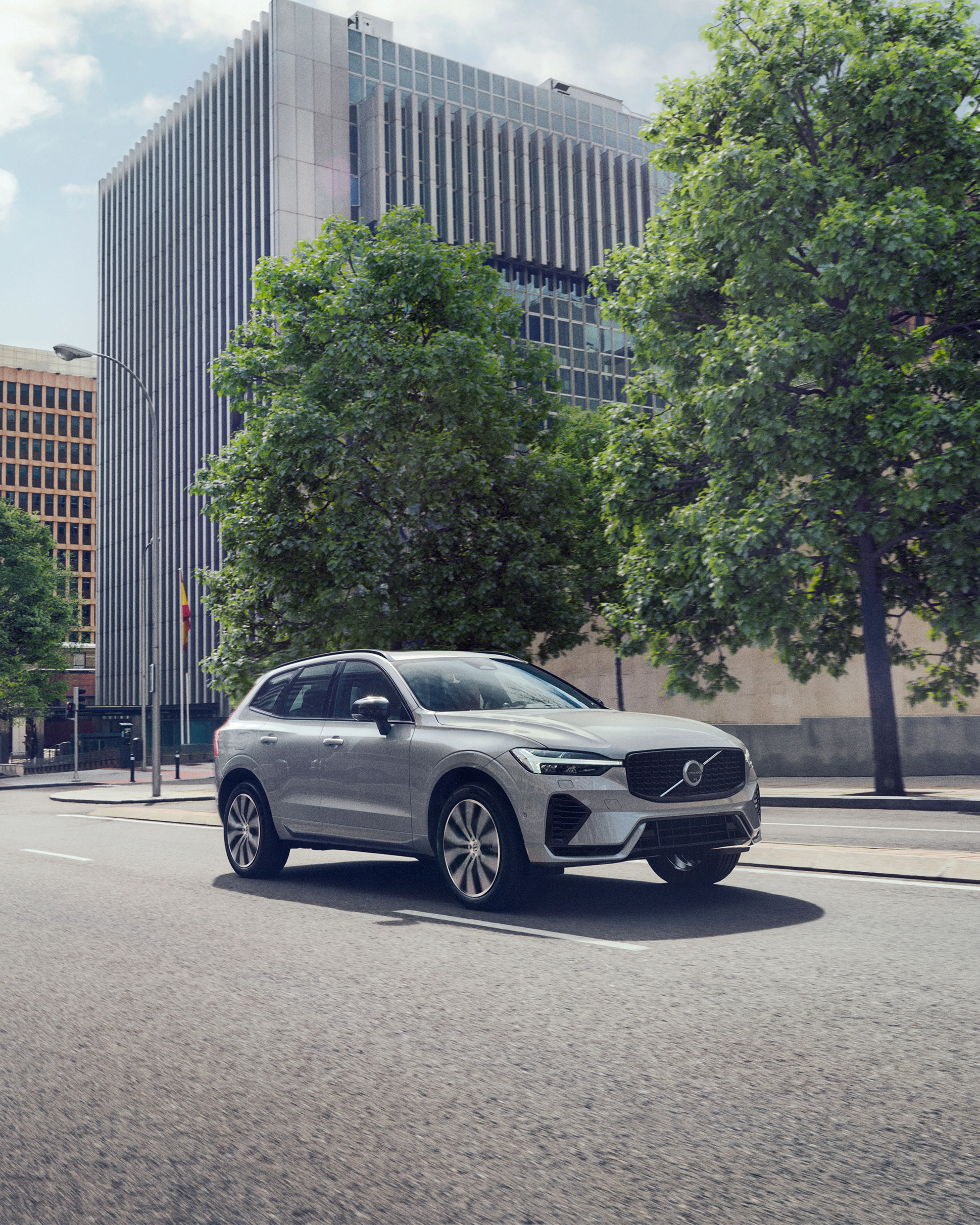 Silvrig Volvo XC60 Recharge kör på en väg