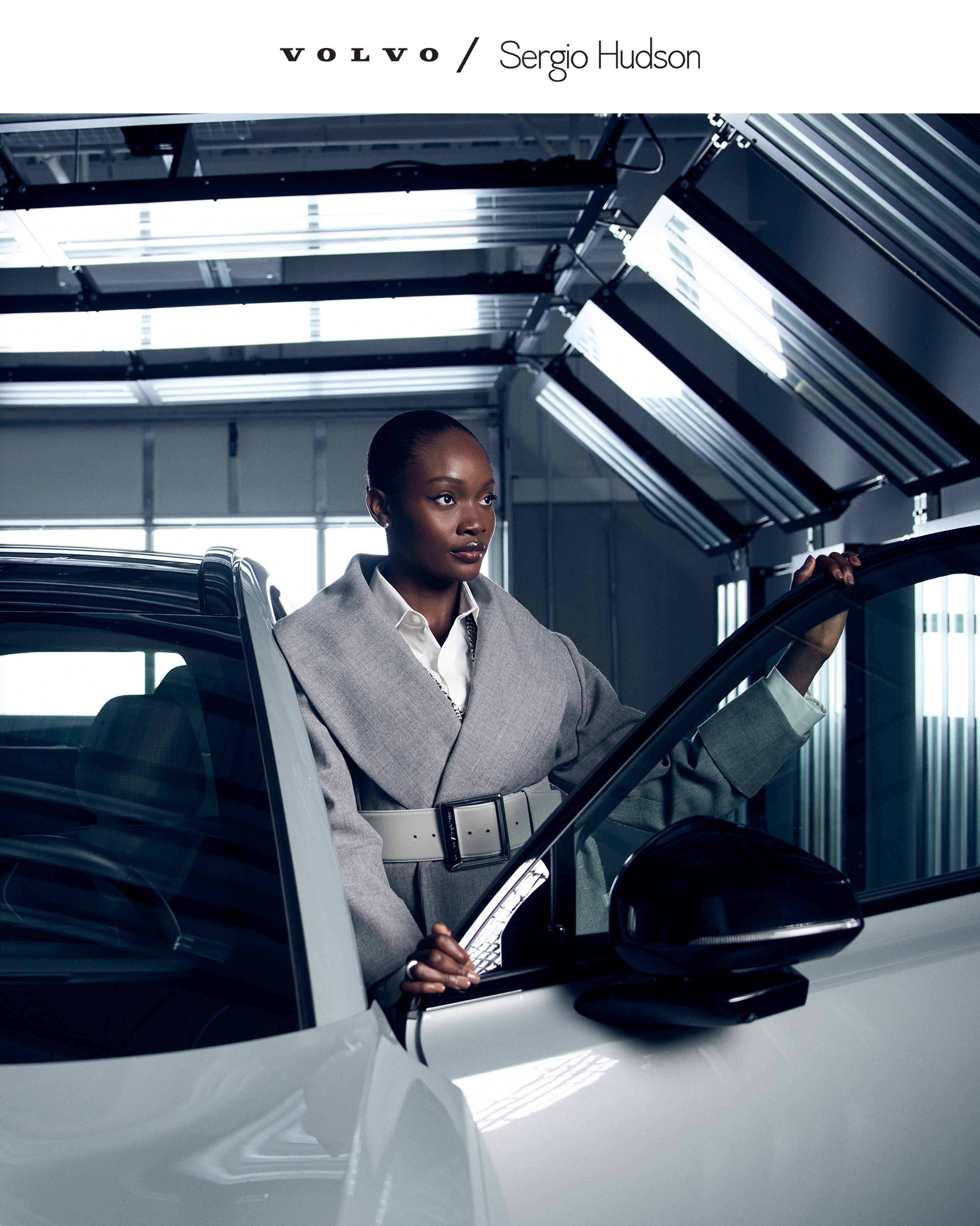 Woman standing next to Volvo EX90 SUV wearing Segio Hudson collection