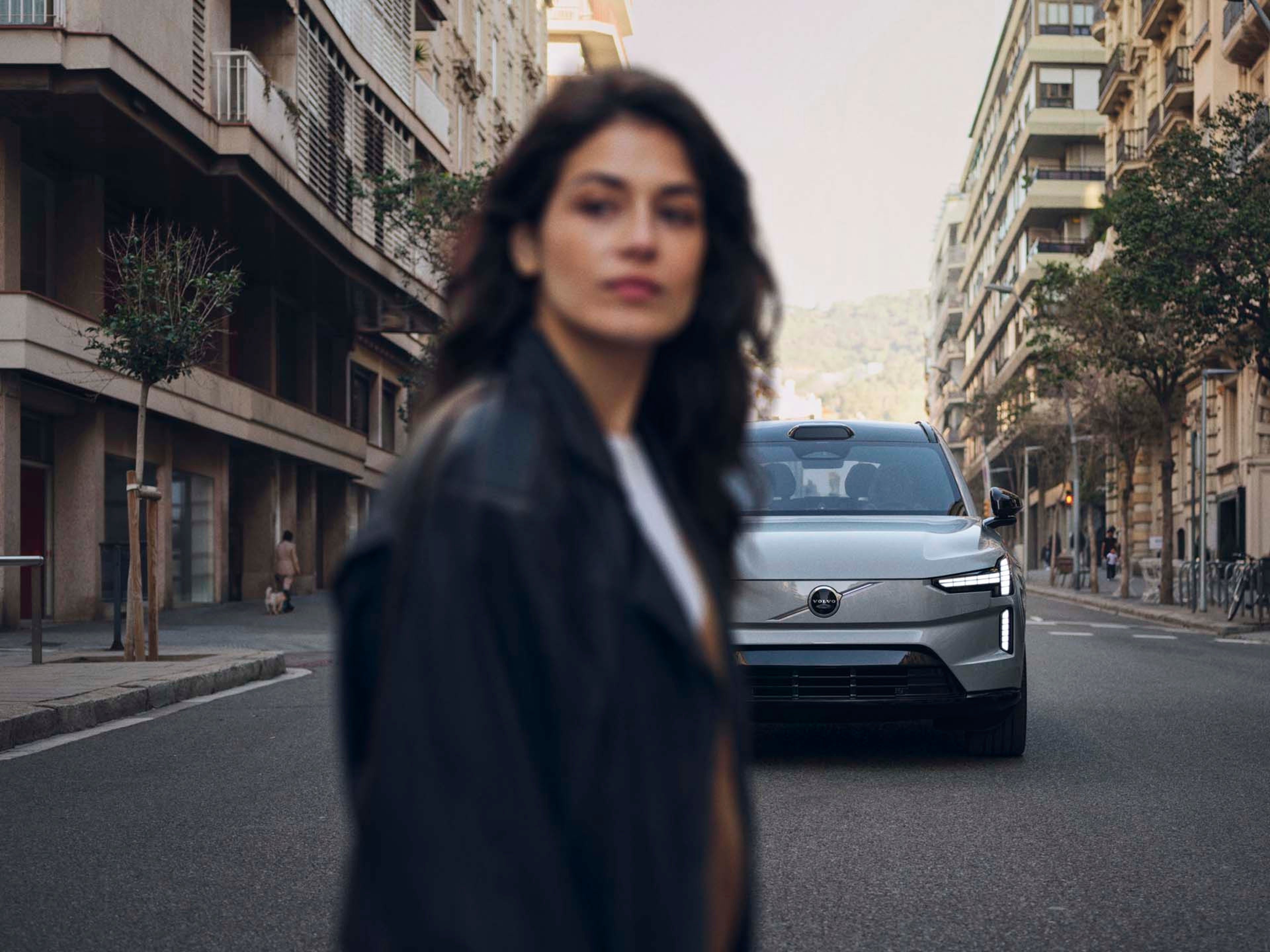 Mujer cruzando la calle y un Volvo EX90 a la espalda