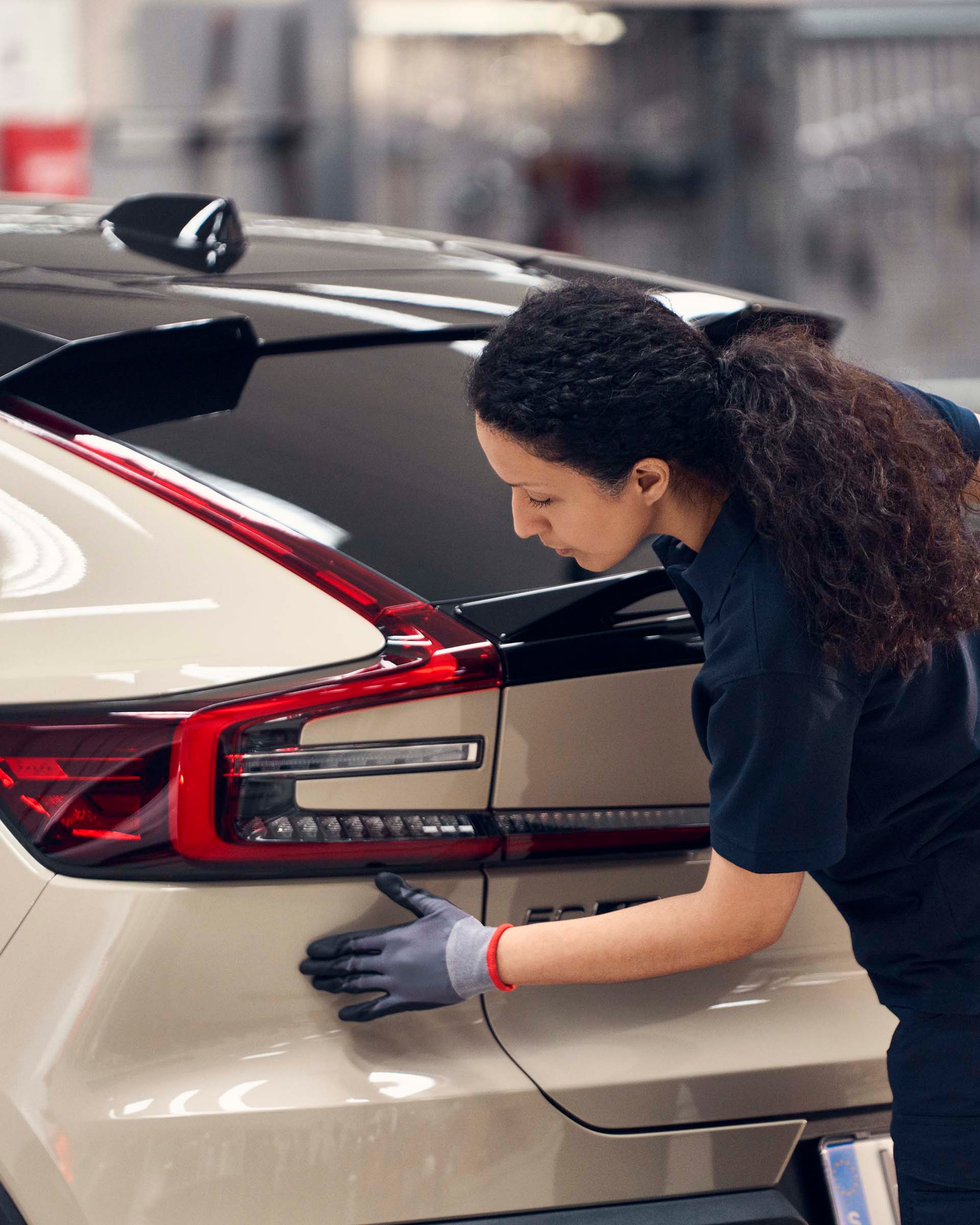 Una mecánica haciendo una comprobación de carrocería en un vehículo Volvo en un concesionario oficial.