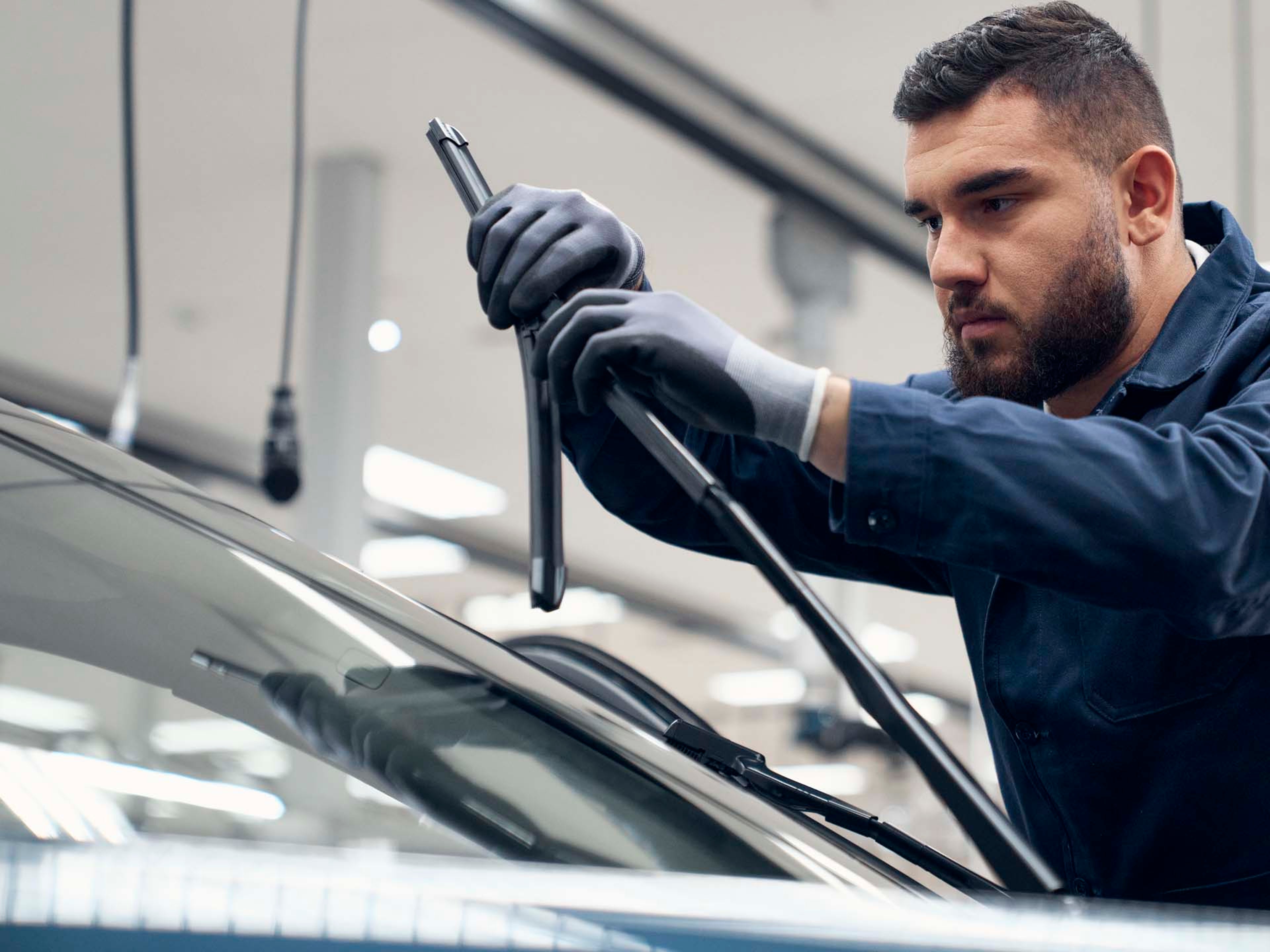 Un mecánico realizando una tarea de mantenimiento de un vehículo Volvo cambiando las escobillas del limpia parabrisas