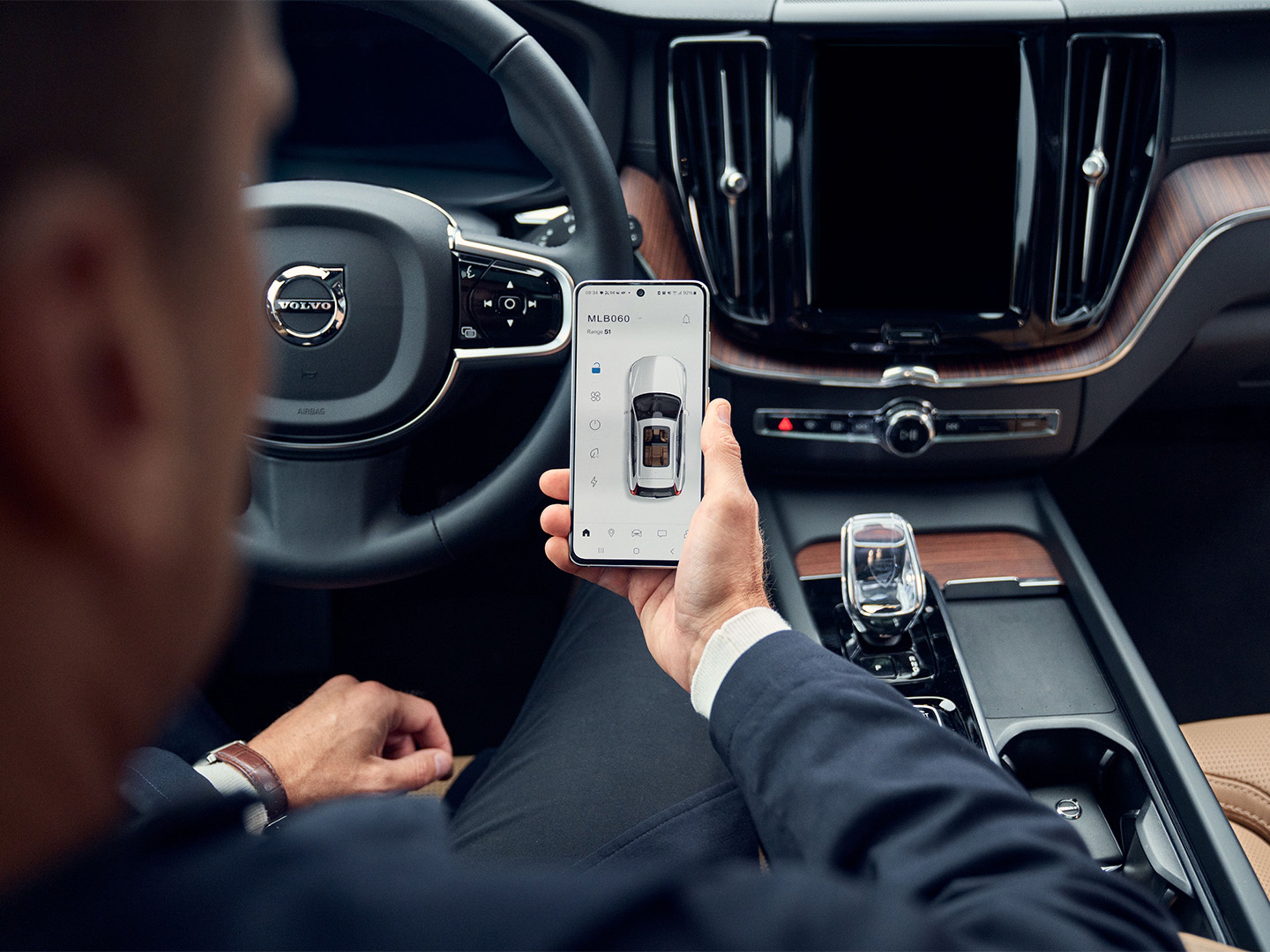 Una persona mirando su teléfono móvil y realizando una reserva en un servicio oficial Volvo.