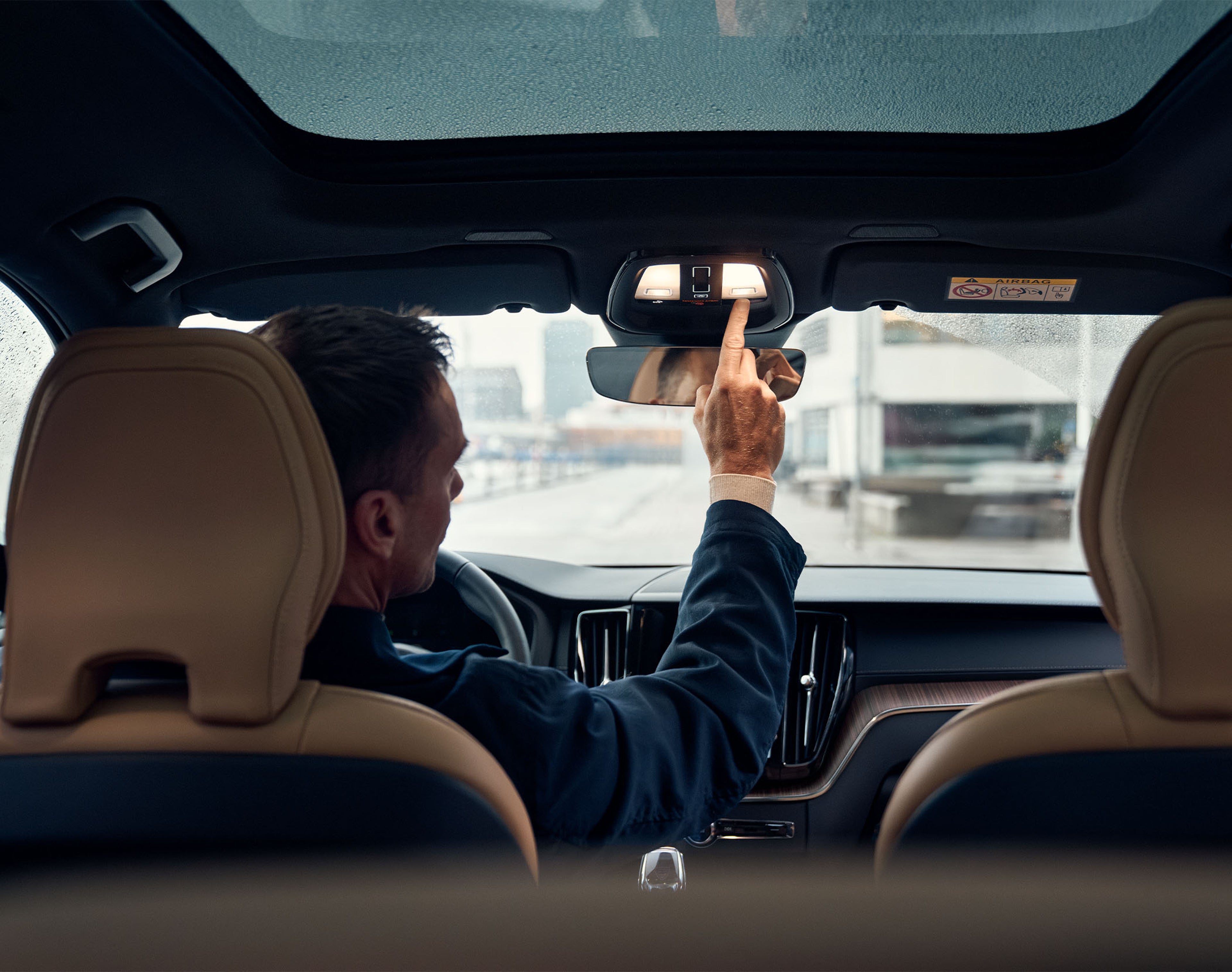 Person pressing button in overhead console in Volvo