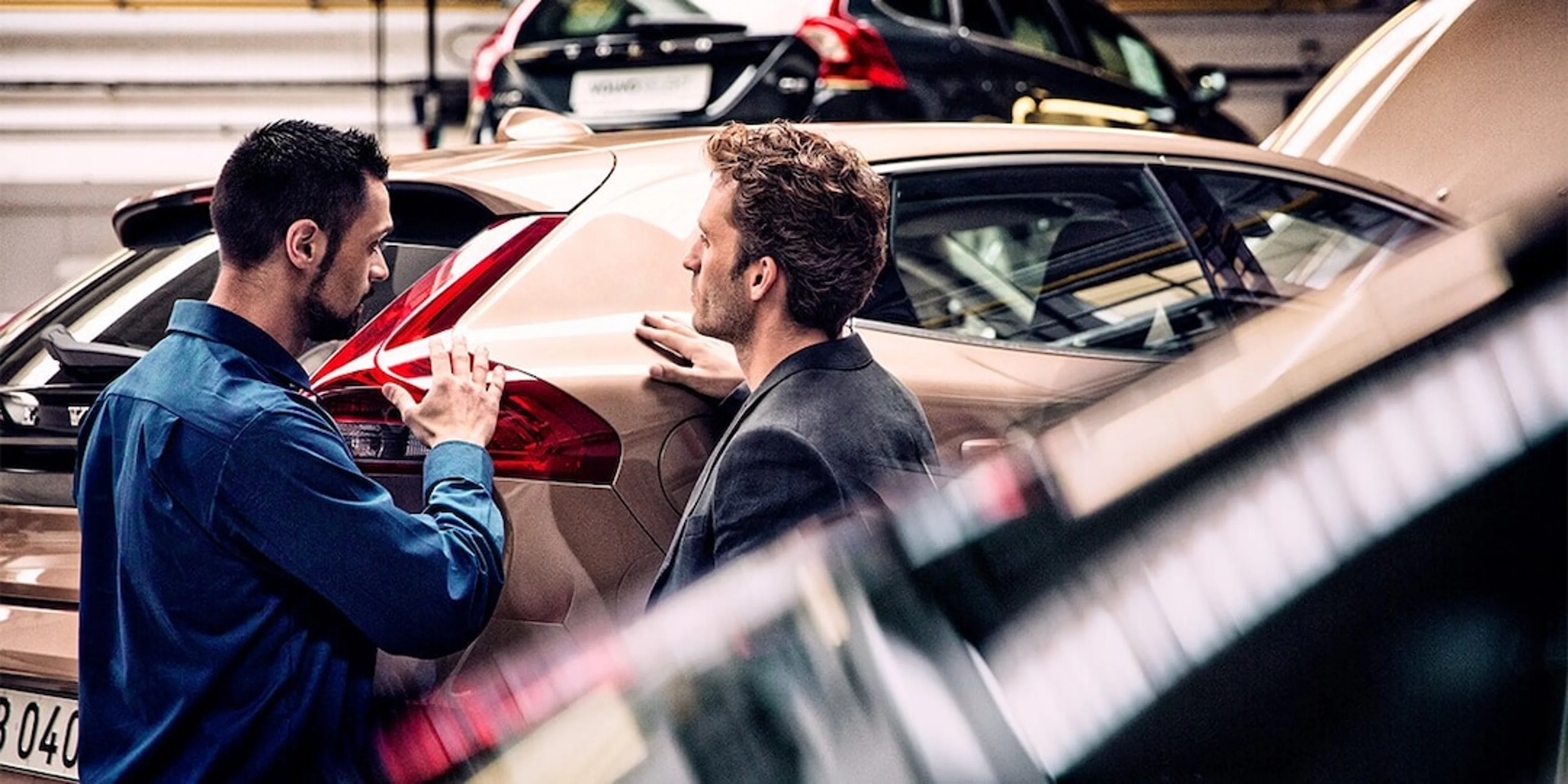 Zwei Männer stehen in einer Werkstatt an einem Volvo Fahrzeug und unterhalten sich.