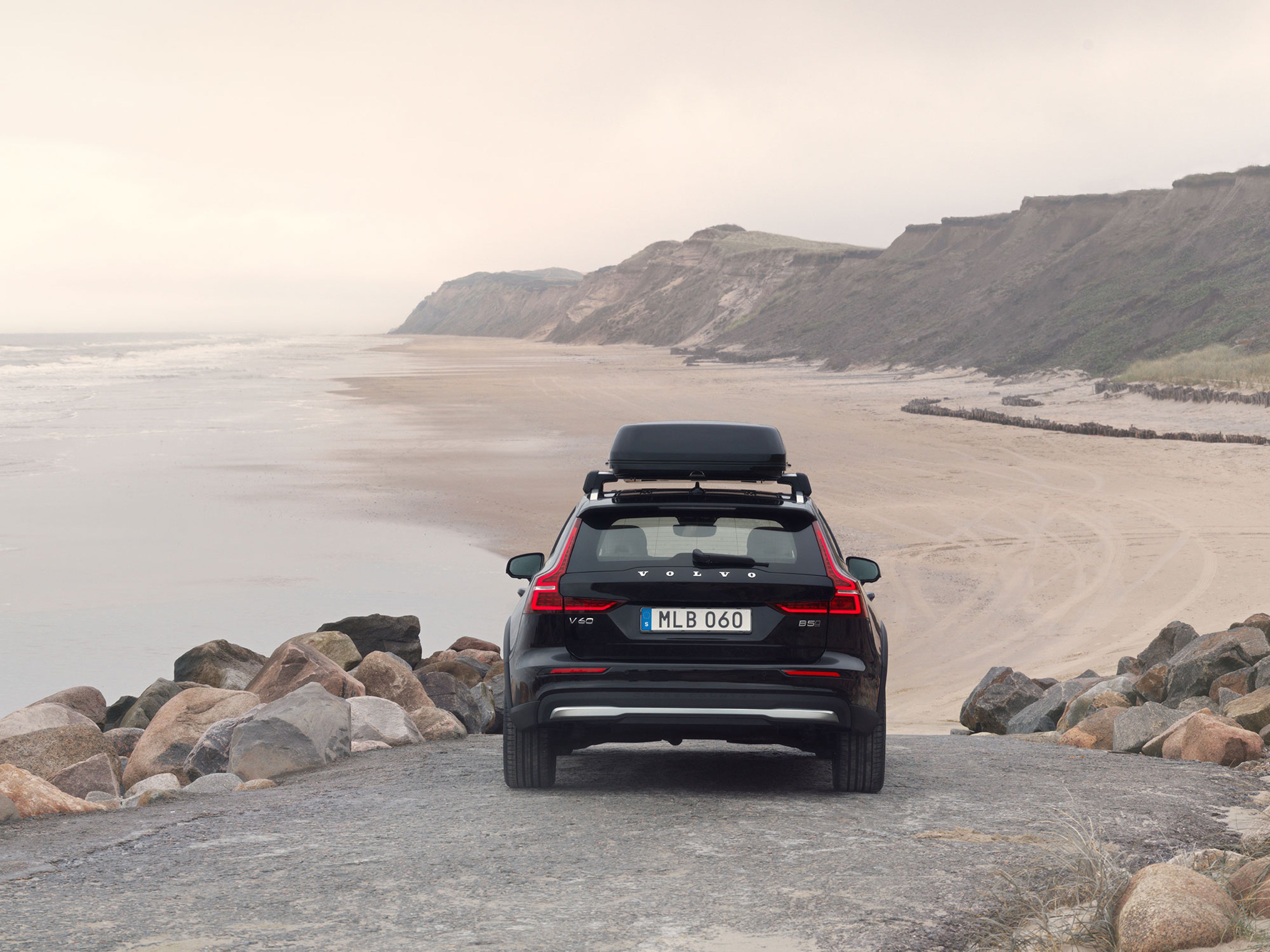 Dakkoffer op een zwarte Volvo V60 geparkeerd aan een strand