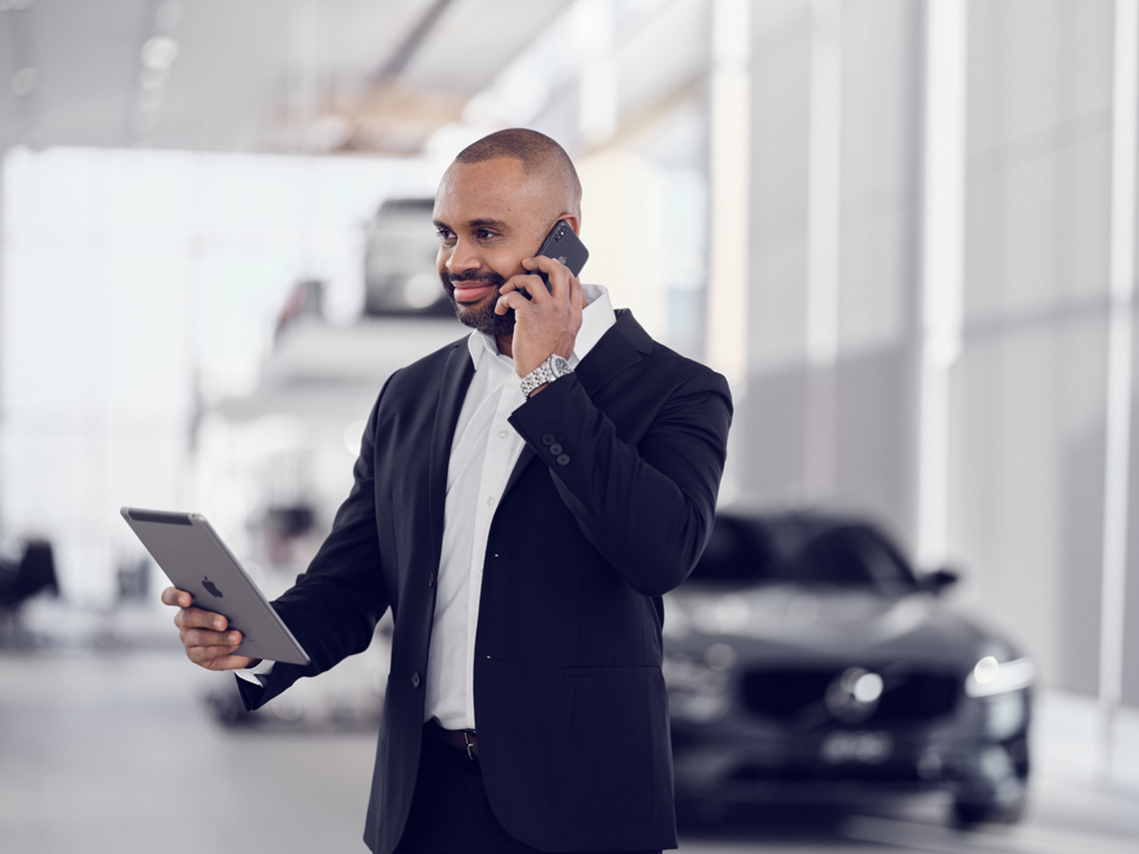 Mann i dress hos forhandler snakker i telefon