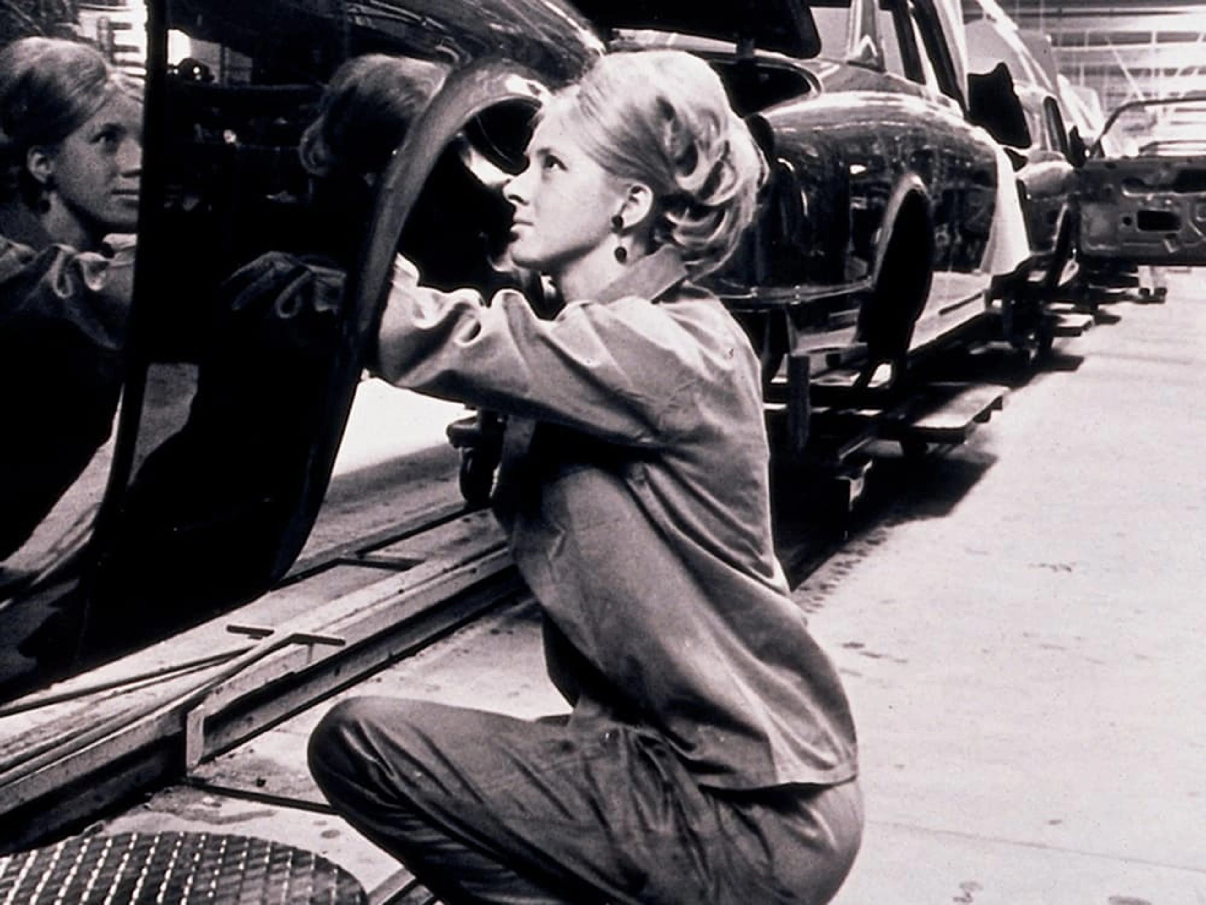 Une photo en noir et blanc d'une femme travaillant sur une voiture dans l'usine automobile Volvo Car Gent dans les années 1970.