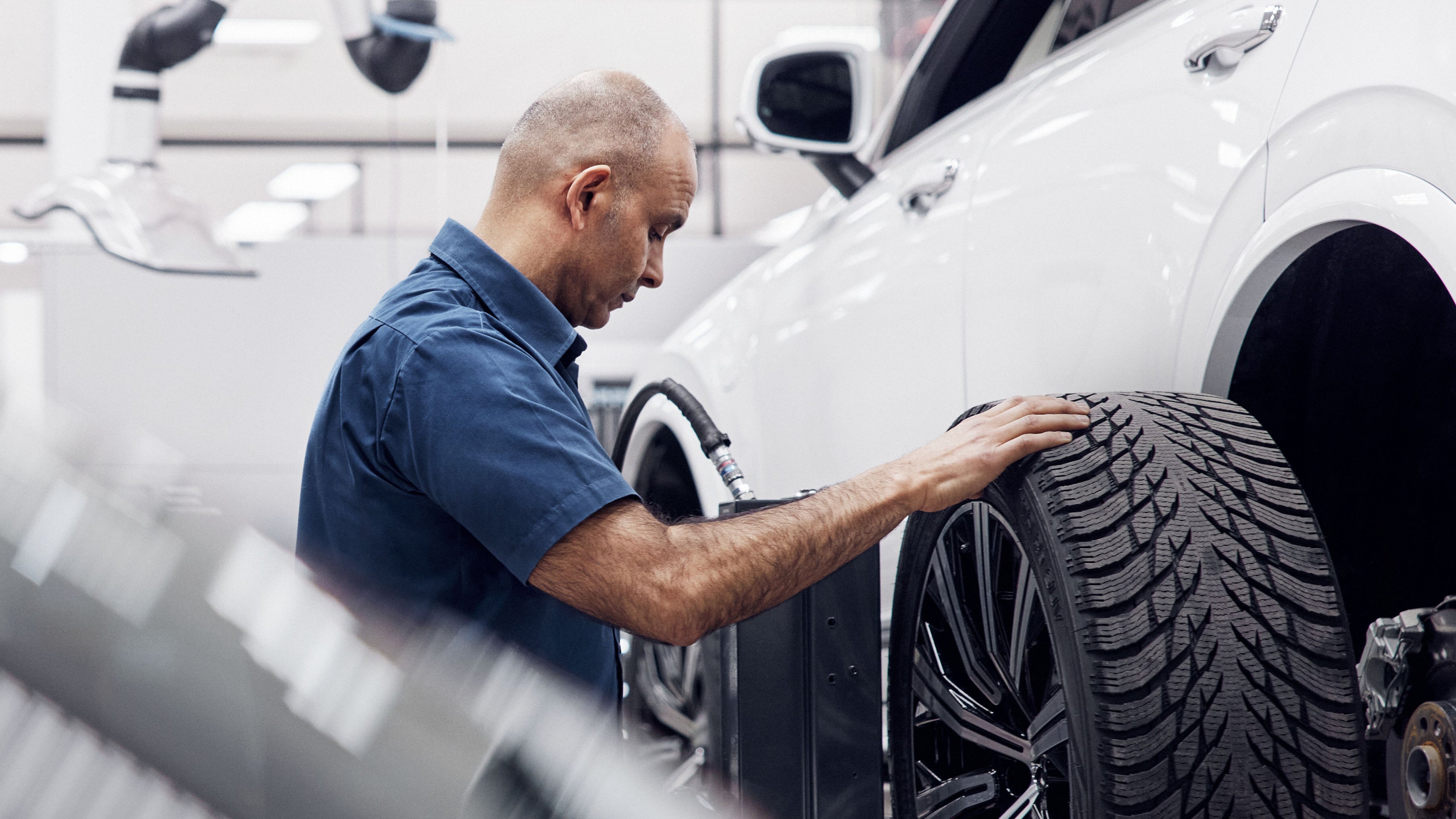 Ein Volvo Mitarbeiter bringt einen Reifen an ein Fahrzeug an.