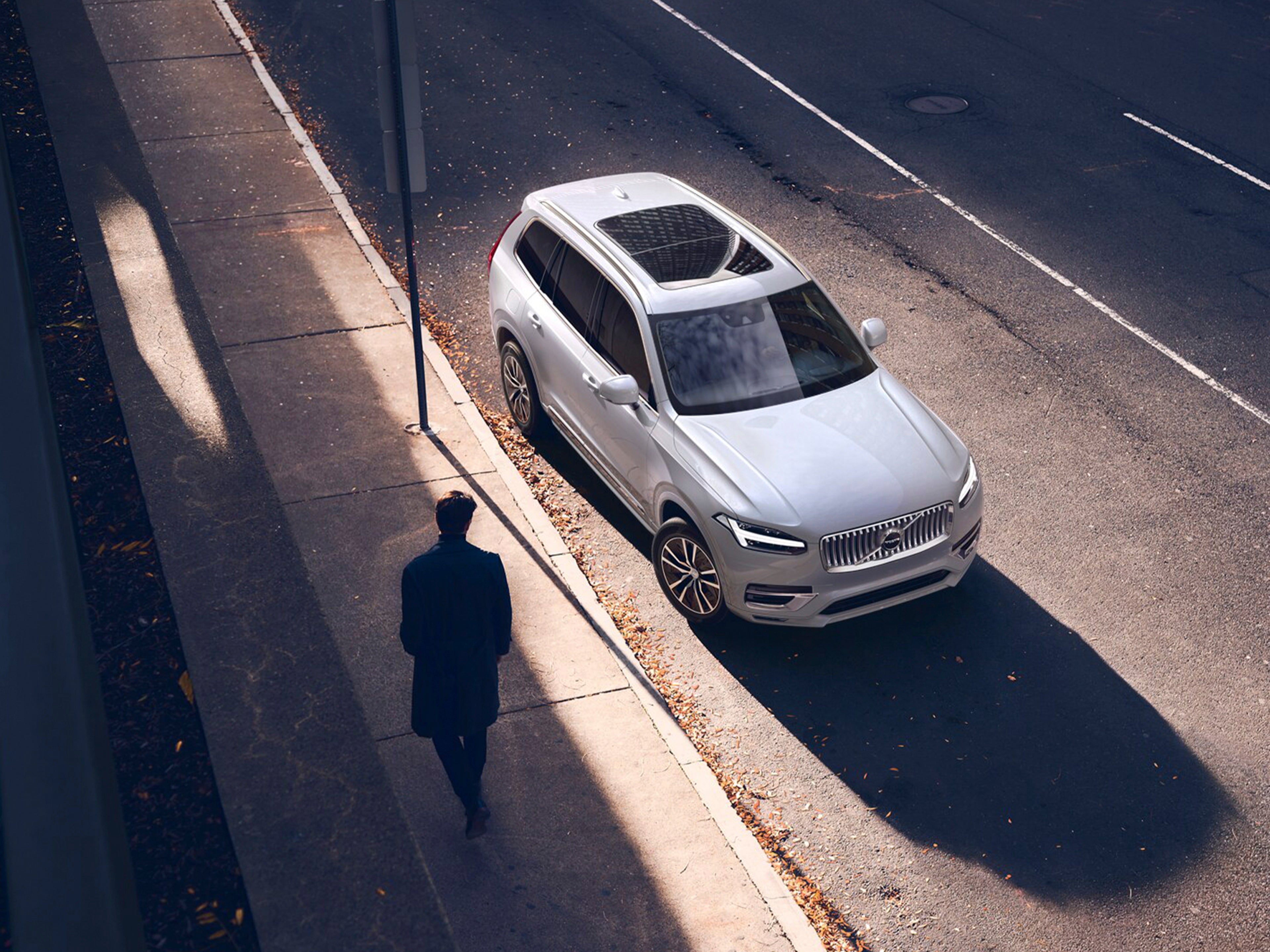 Volvo XC90 y una persona caminando sobre la banqueta.