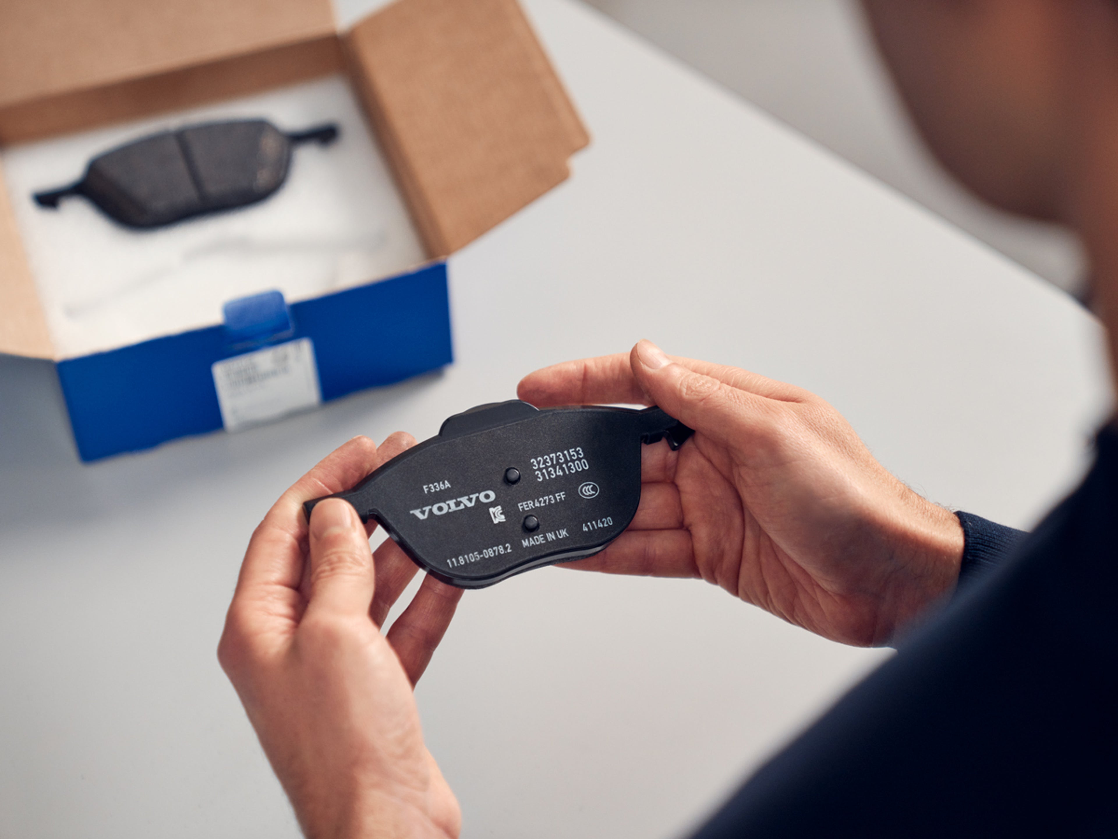 Volvo originaldel - Tekniker håller i ett bromsbelägg.