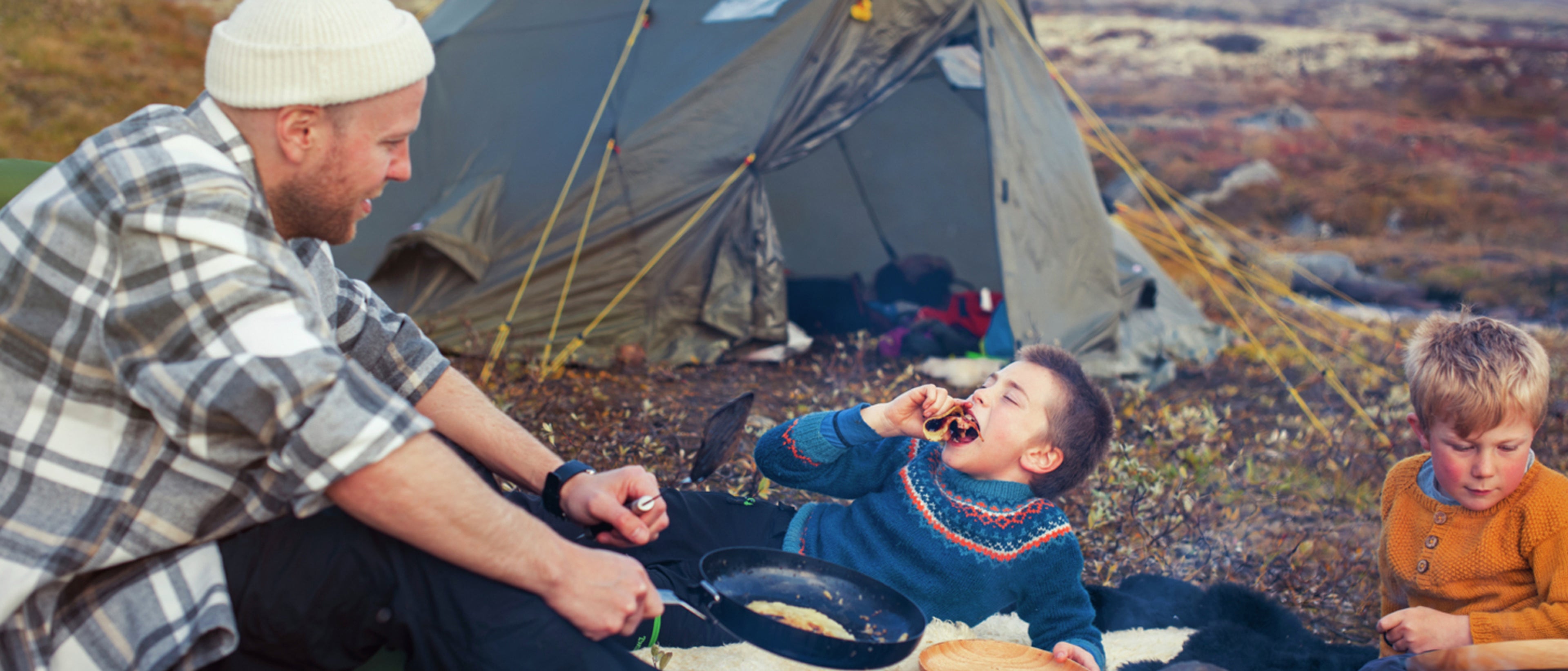 Mann og 2 barn sitter rundt bålet