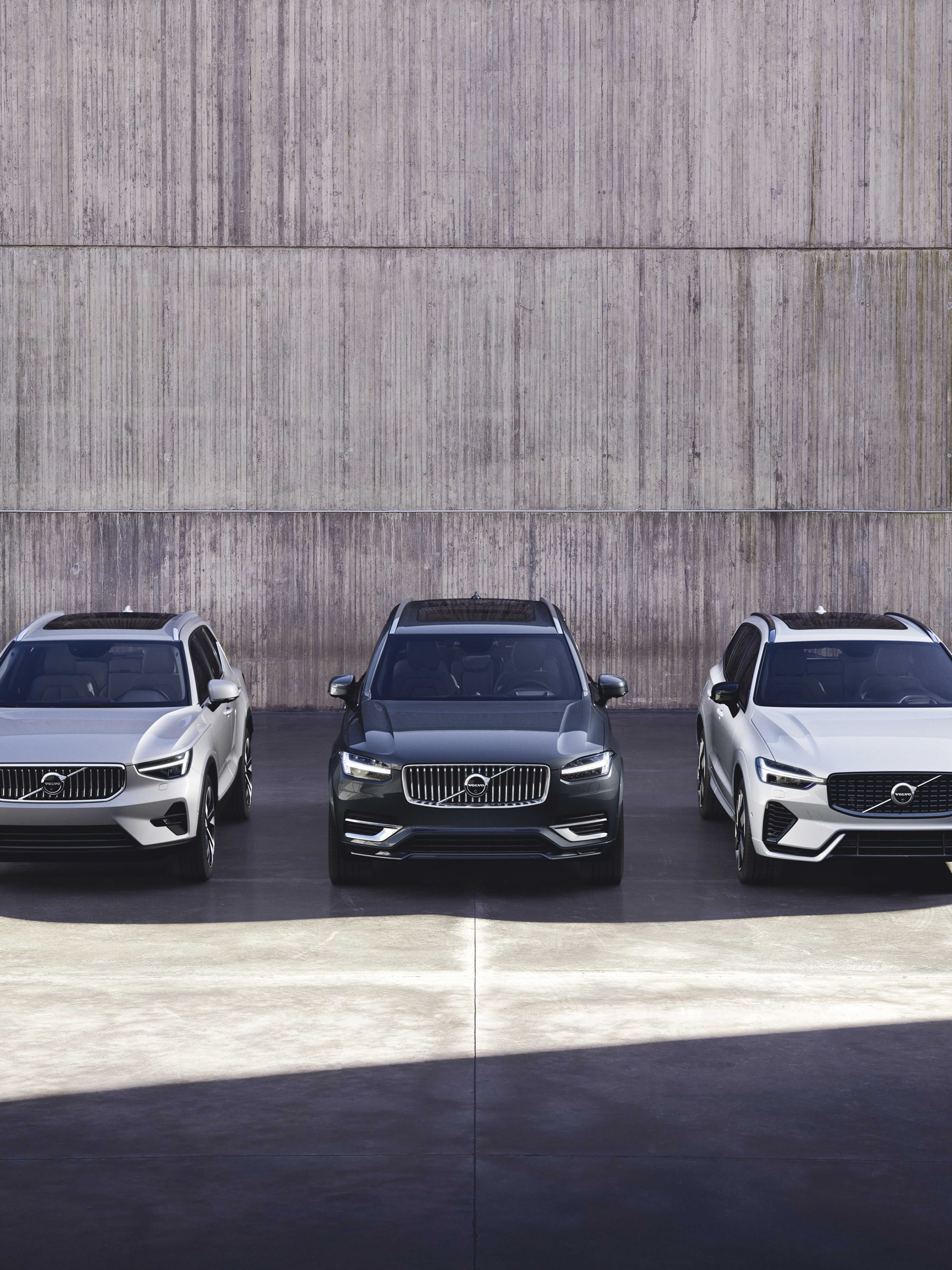 Ett urval av Volvos SUVar fotograferade rakt framifrån mot en betongvägg.