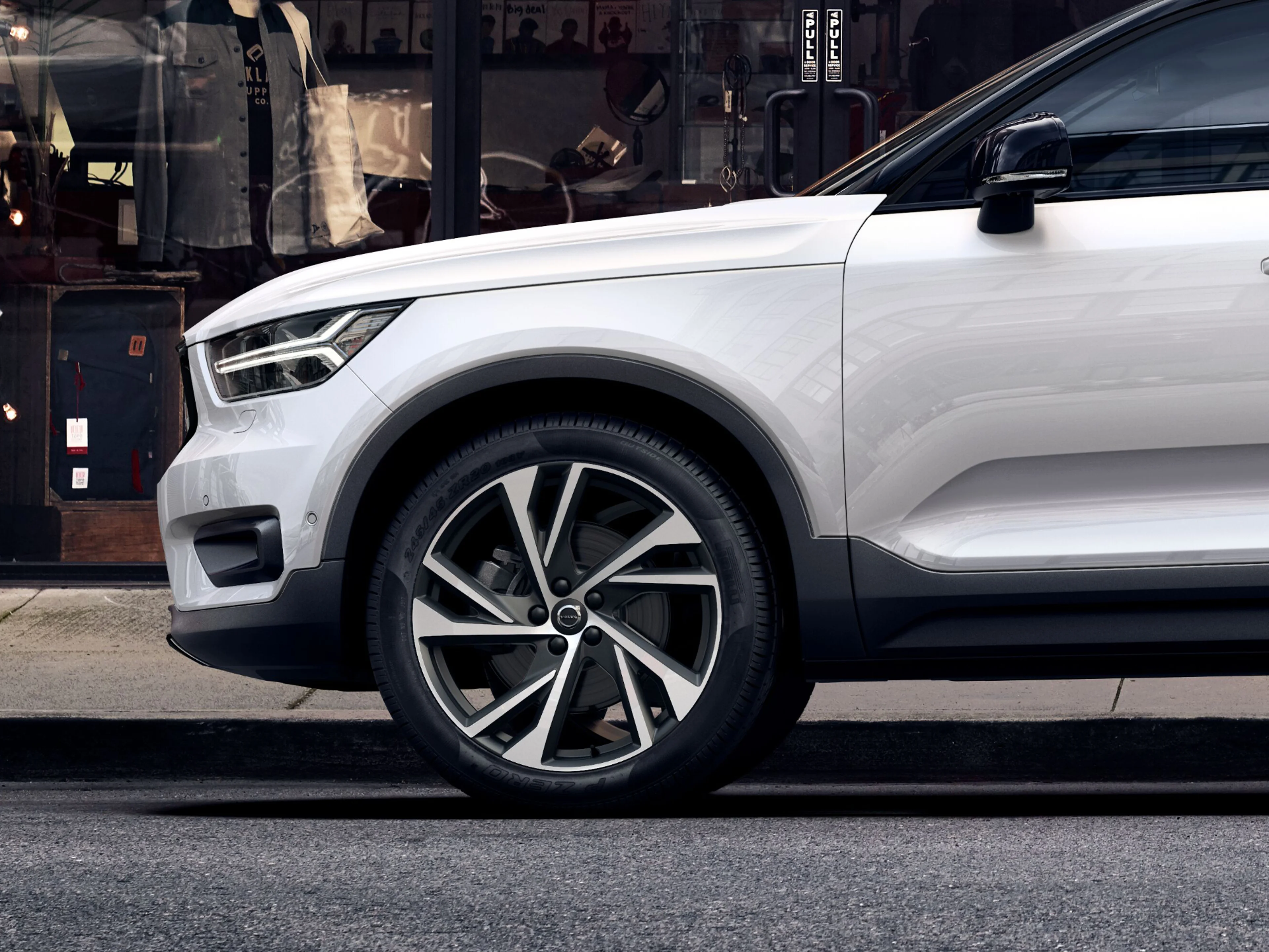 Anschnitt eines weißen Volvo XC40 vor einer Ladenfront.