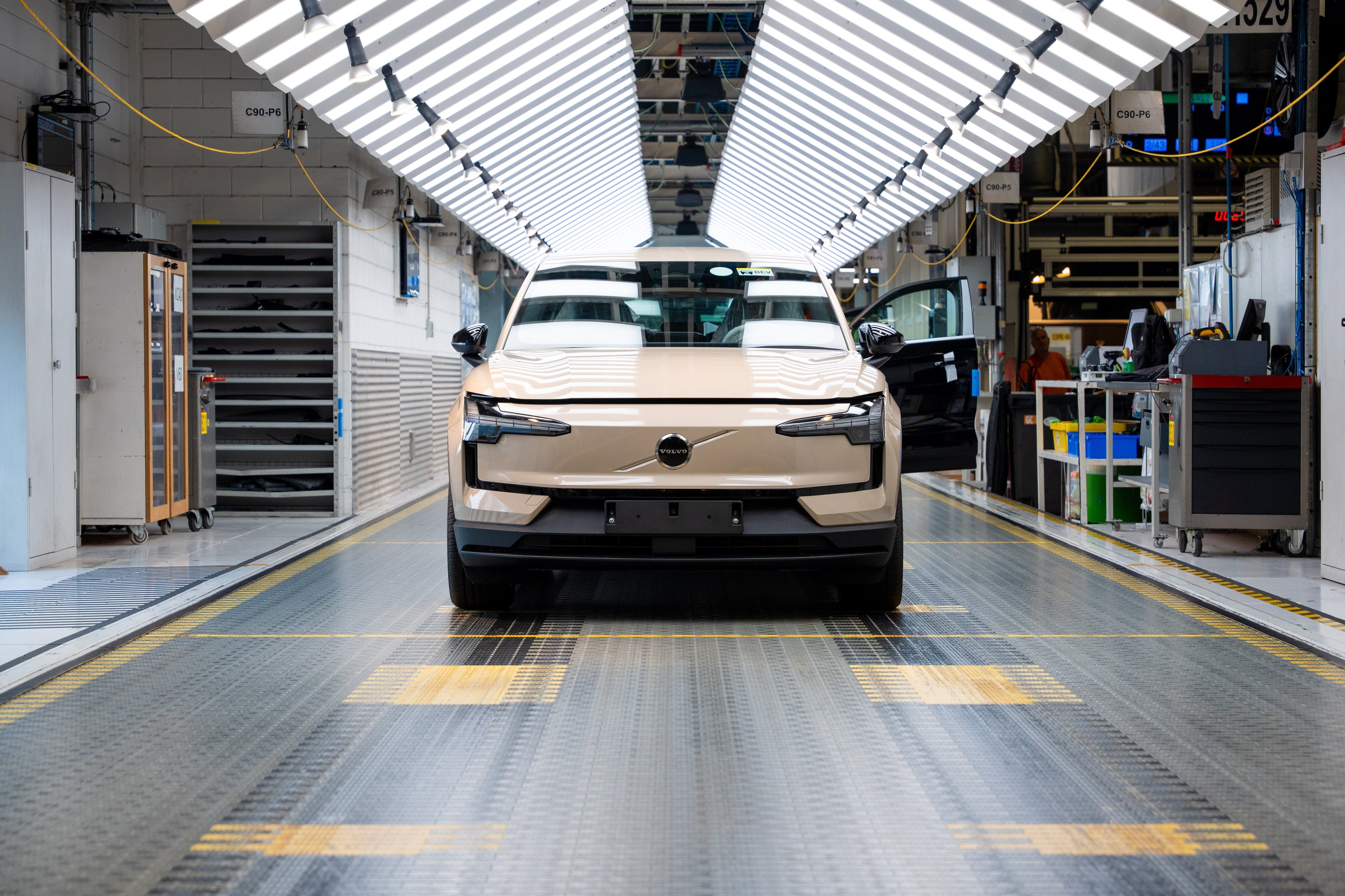Frontansicht eines beigen Volvo EX30 im einer Fabrik.