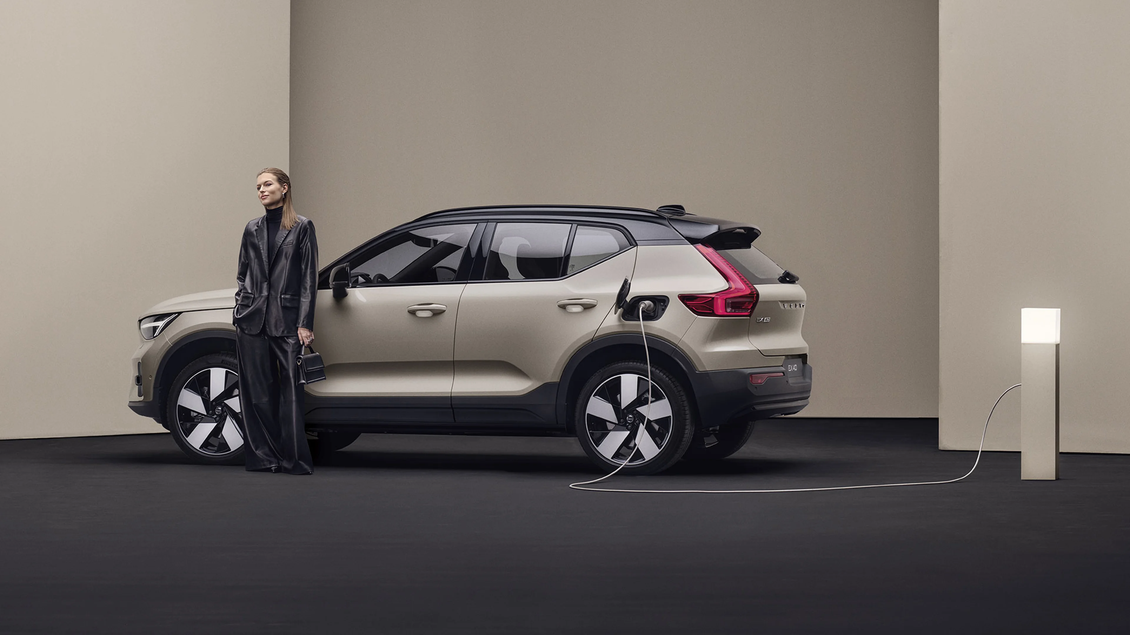 Volvo EX40 électrique branchée à une borne, une personne debout à côté.