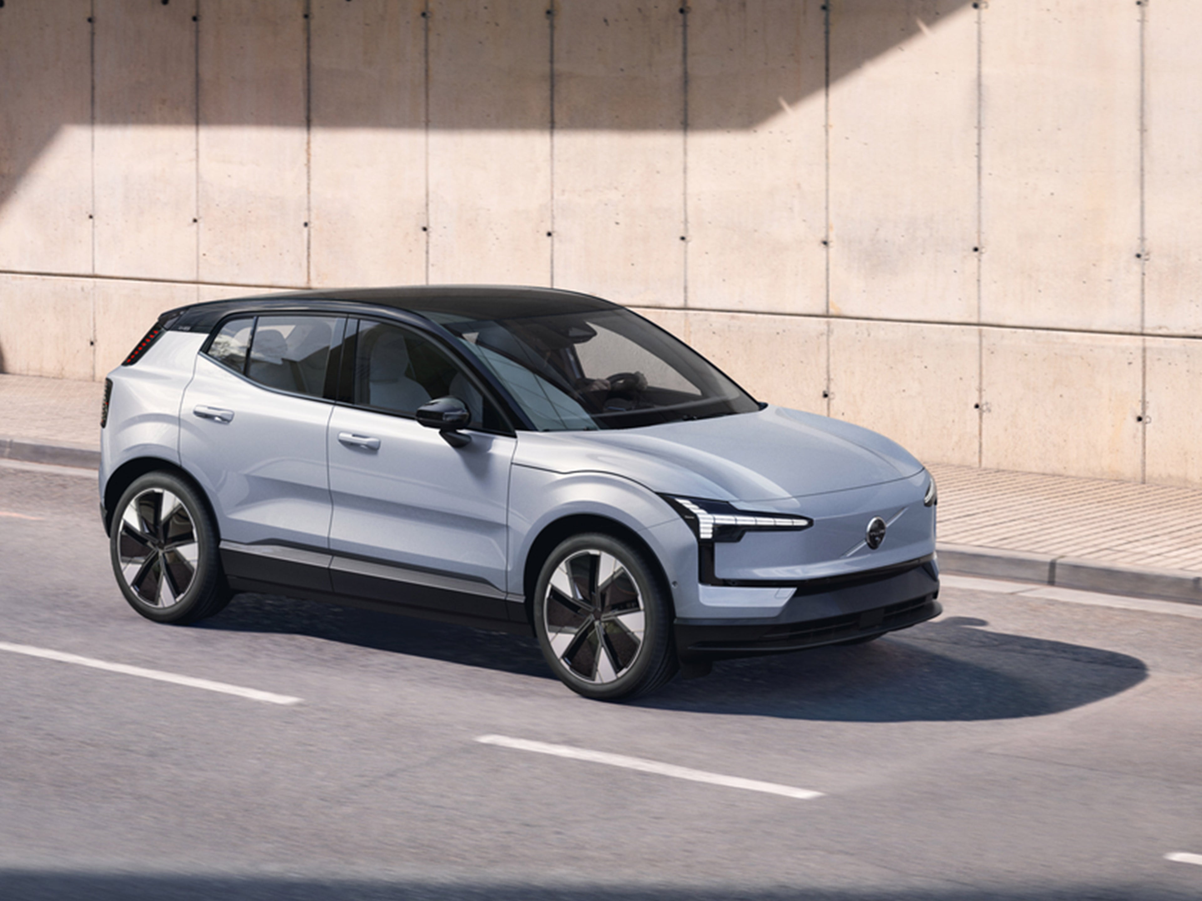 Cloud Blue värinen Volvo EX30 pysäköitynä vaalean betoniseinän eteen.