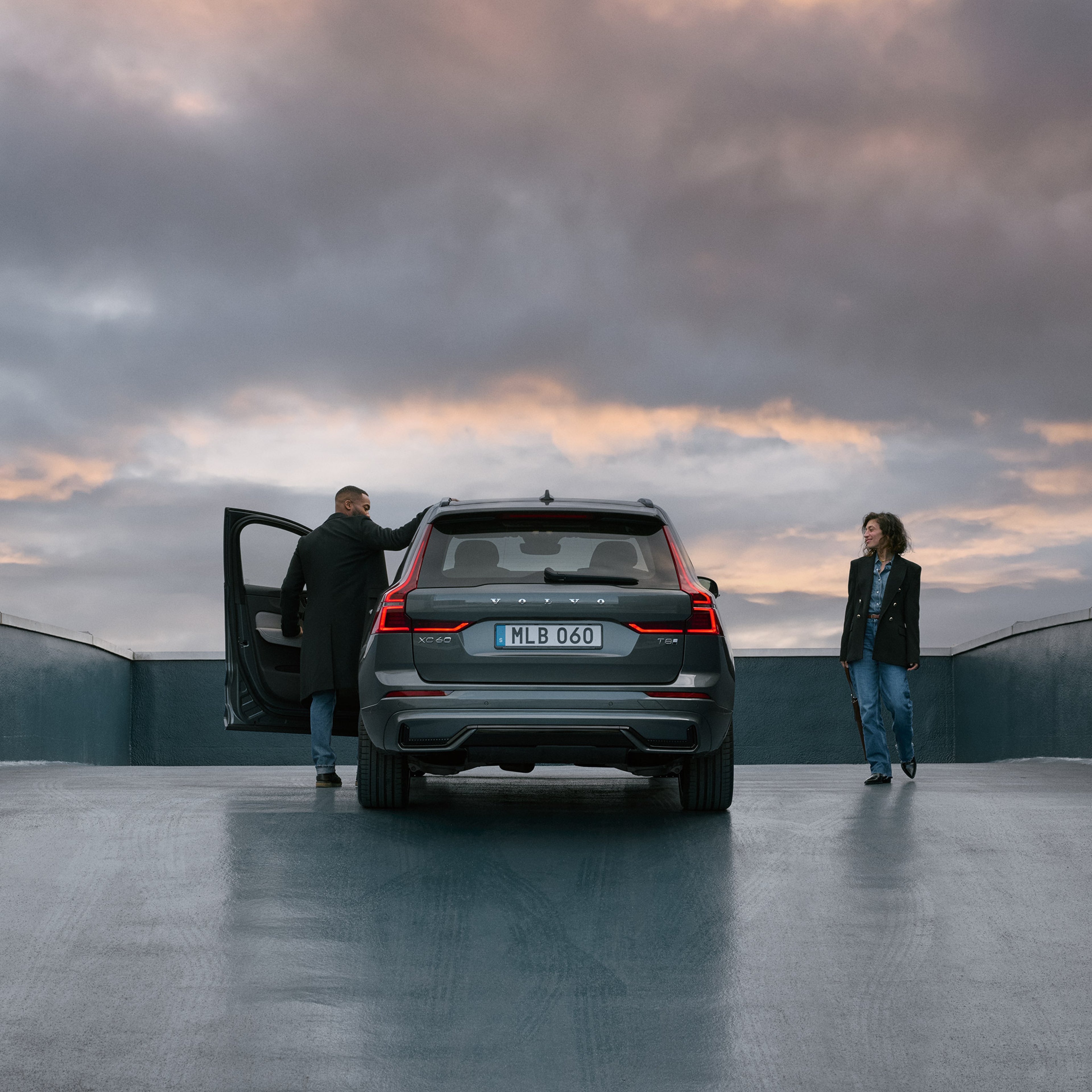 Nainen ja mies seisovat katolle päättyvälle tielle pysäköidyn Forest lake -värisen Volvo XC60 lataushybridikatumaasturin vieressä.