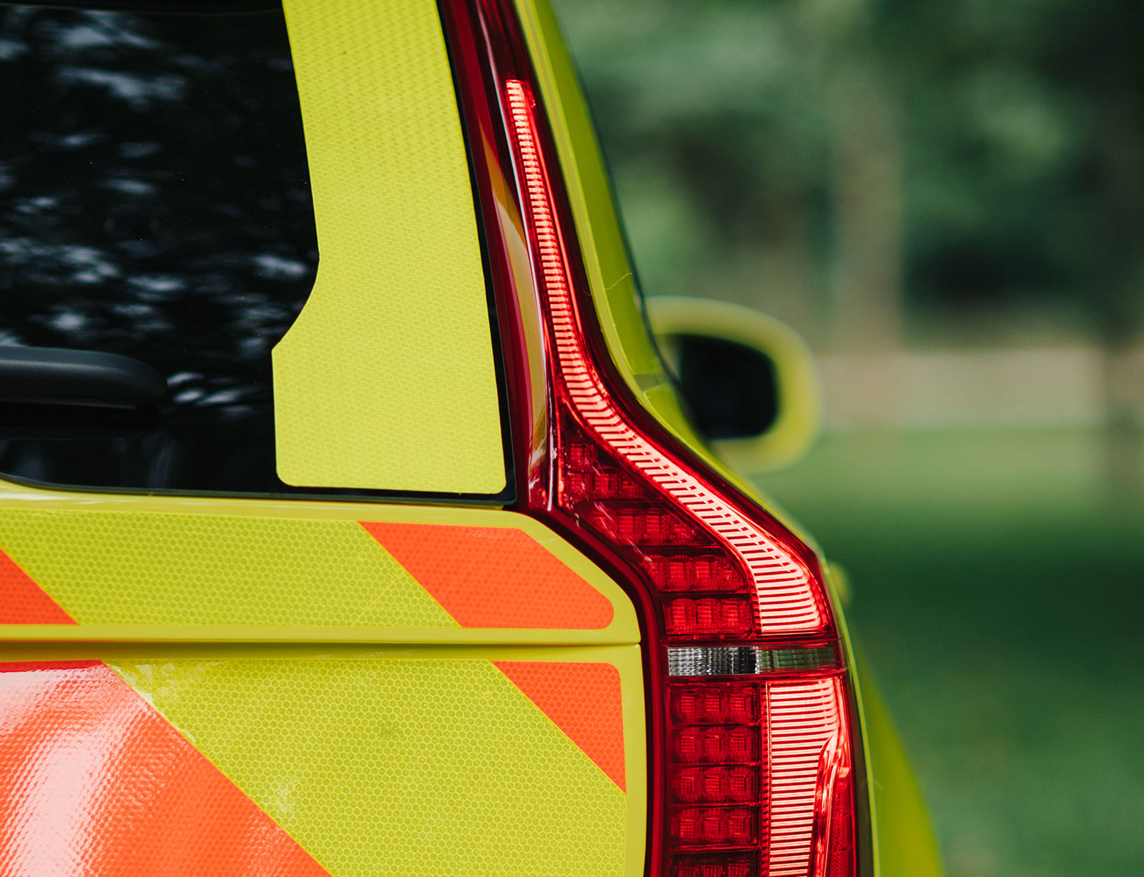 Close-up van het verticale LED-achterlicht van een Volvo hulpverleningsvoertuig met fluorescerende gele en oranje reflecterende markeringen.