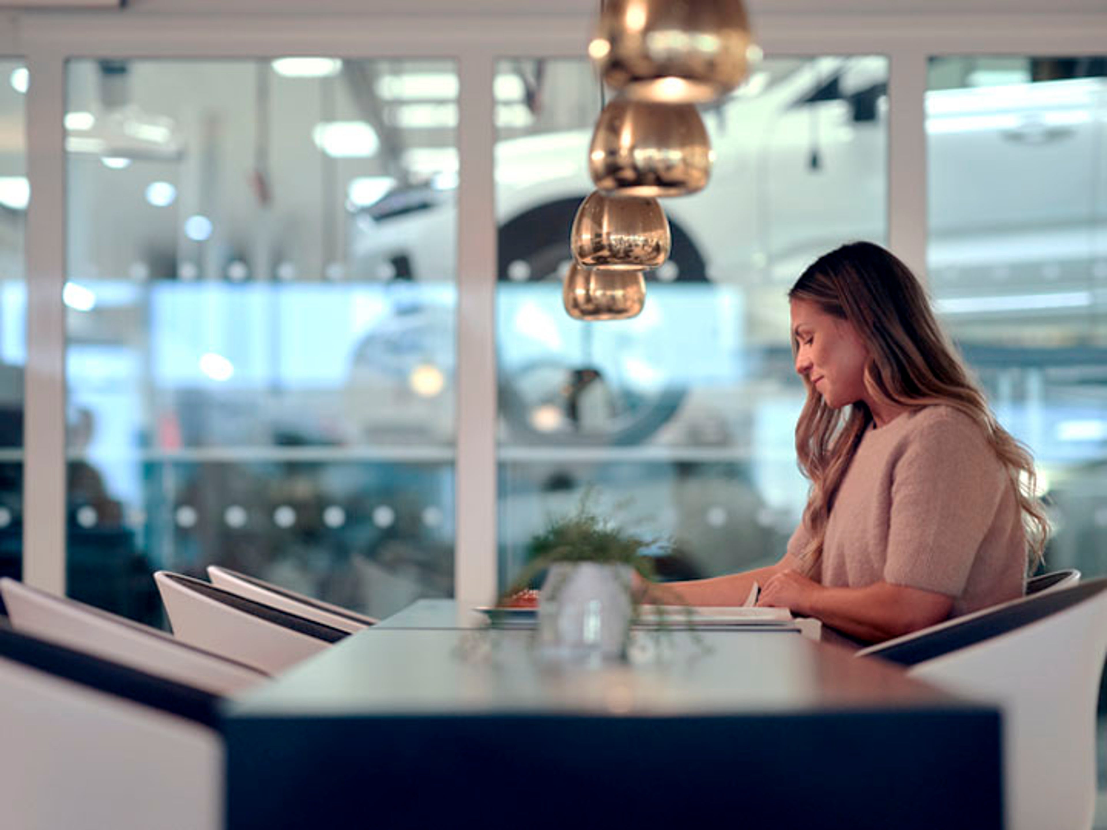 Una mujer leyendo y esperando en un taller Volvo
