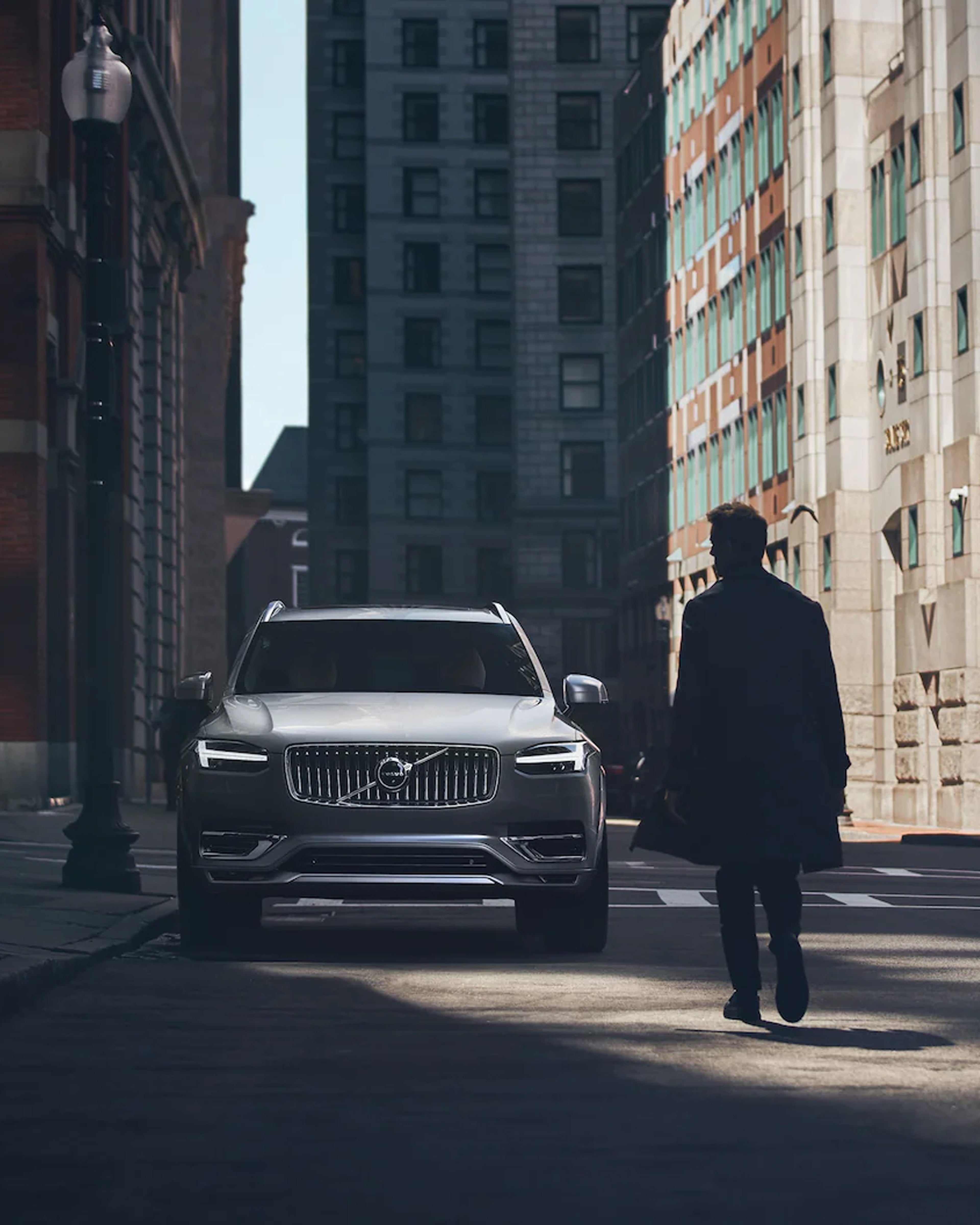 Mann går mot en sølv XC90 i byen