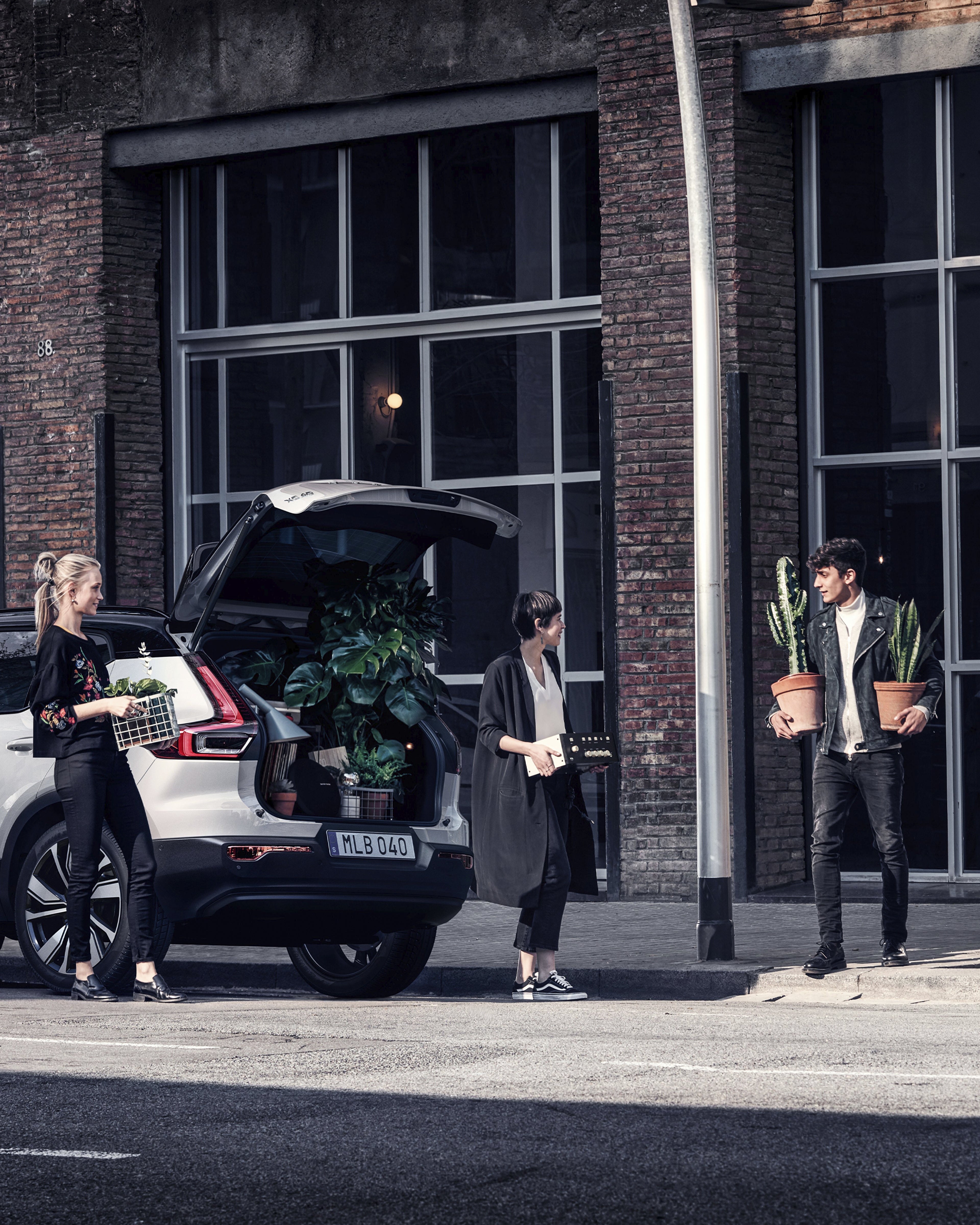 Un grupo de personas cargando cosas en la cajuela de un volvo XC40.