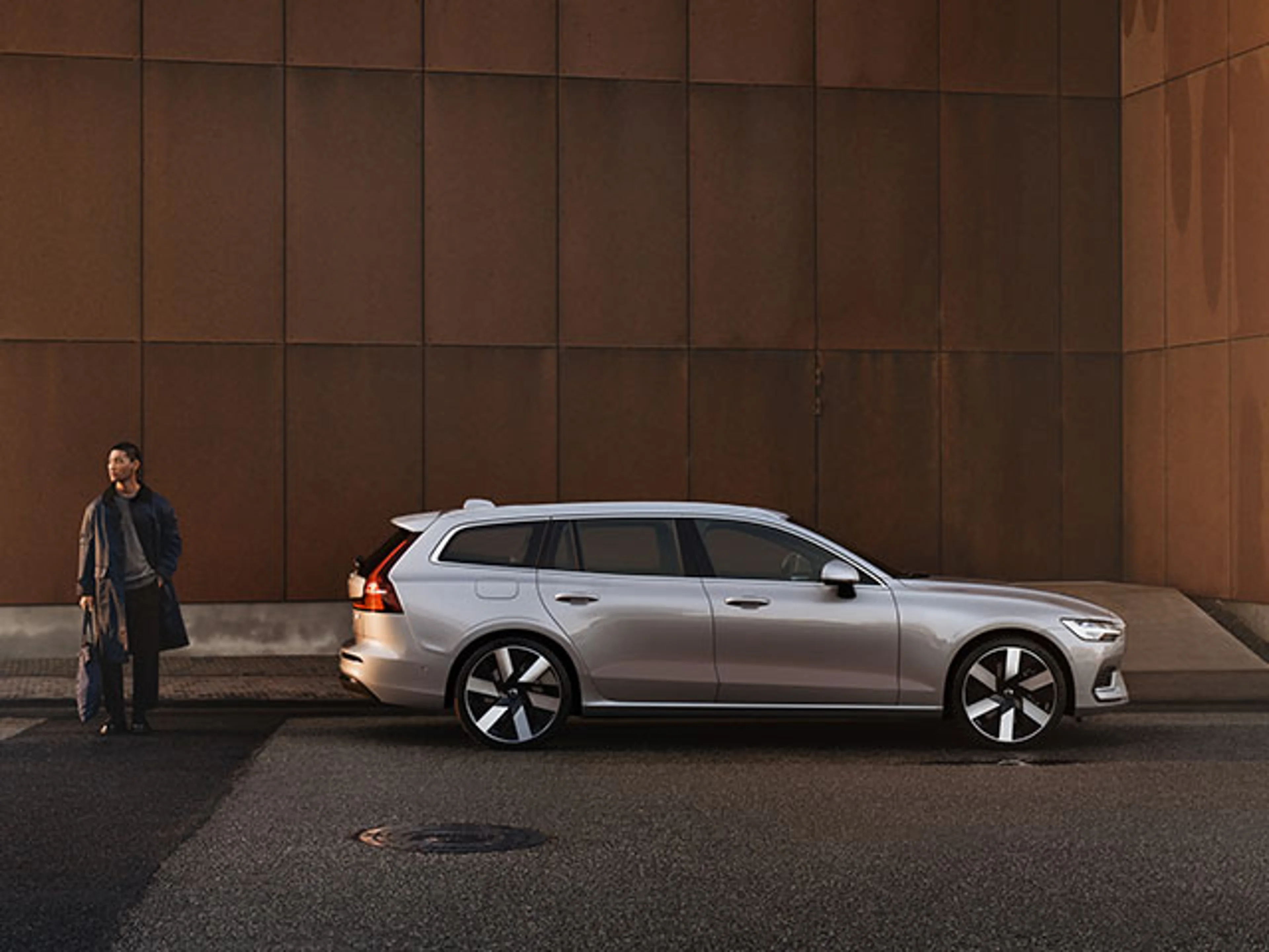 Man står bredvid silvrig Volvo V60 laddhybrid