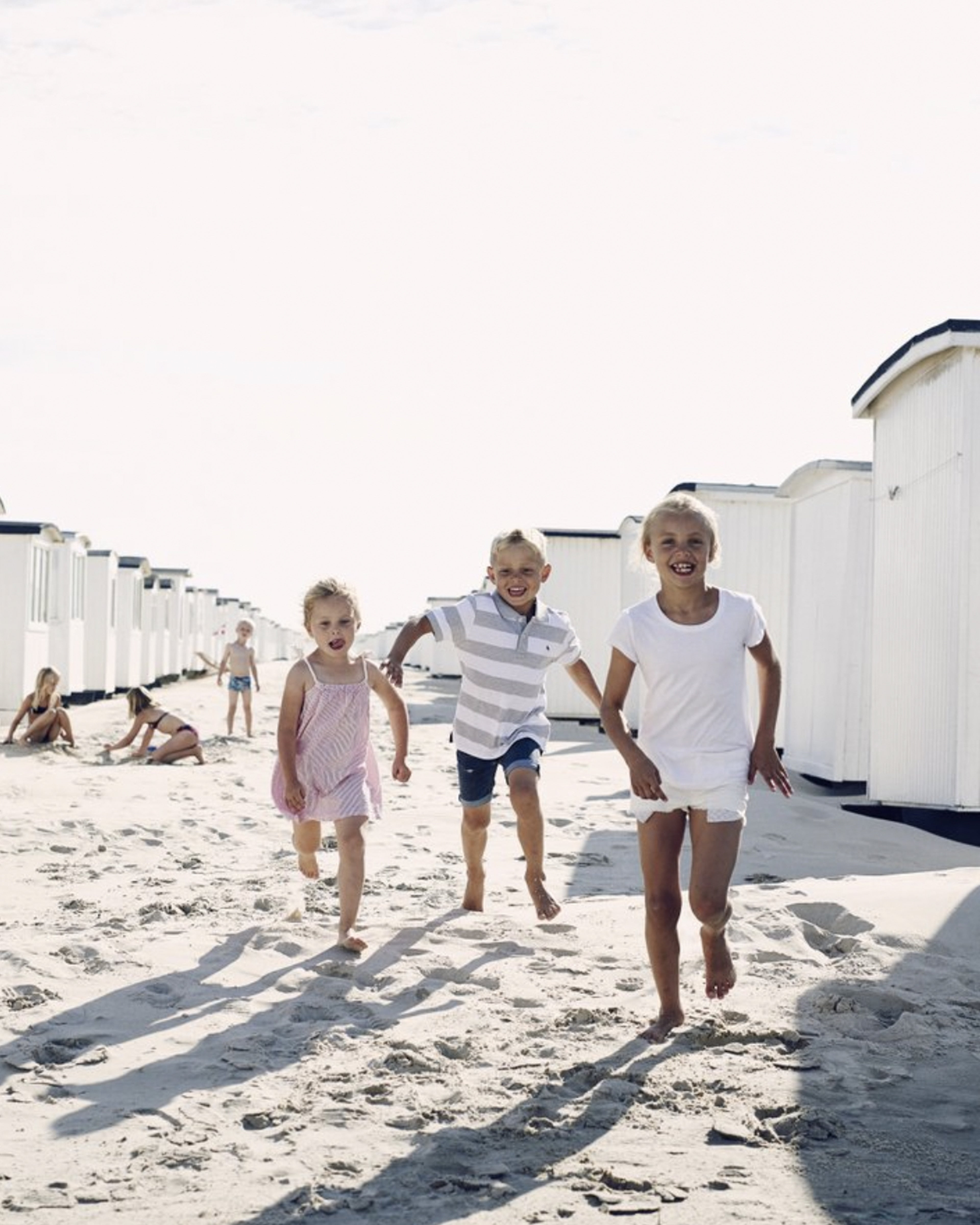 3 barn løpende og smilende på en strand