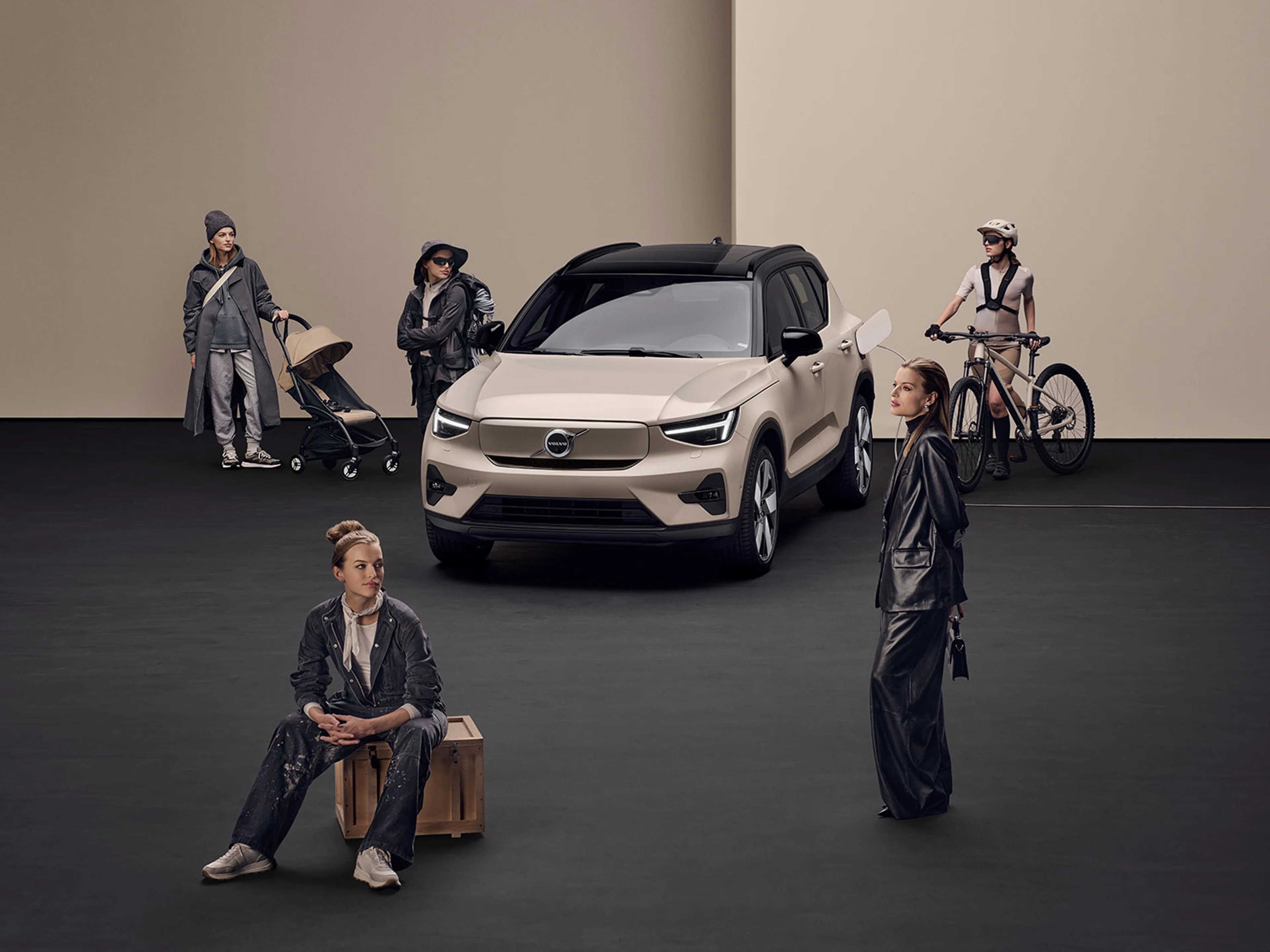 Des personnes avec des bagages, dont une poussette et un vélo, se tiennent à côté d'une Volvo EX30 dans un studio.