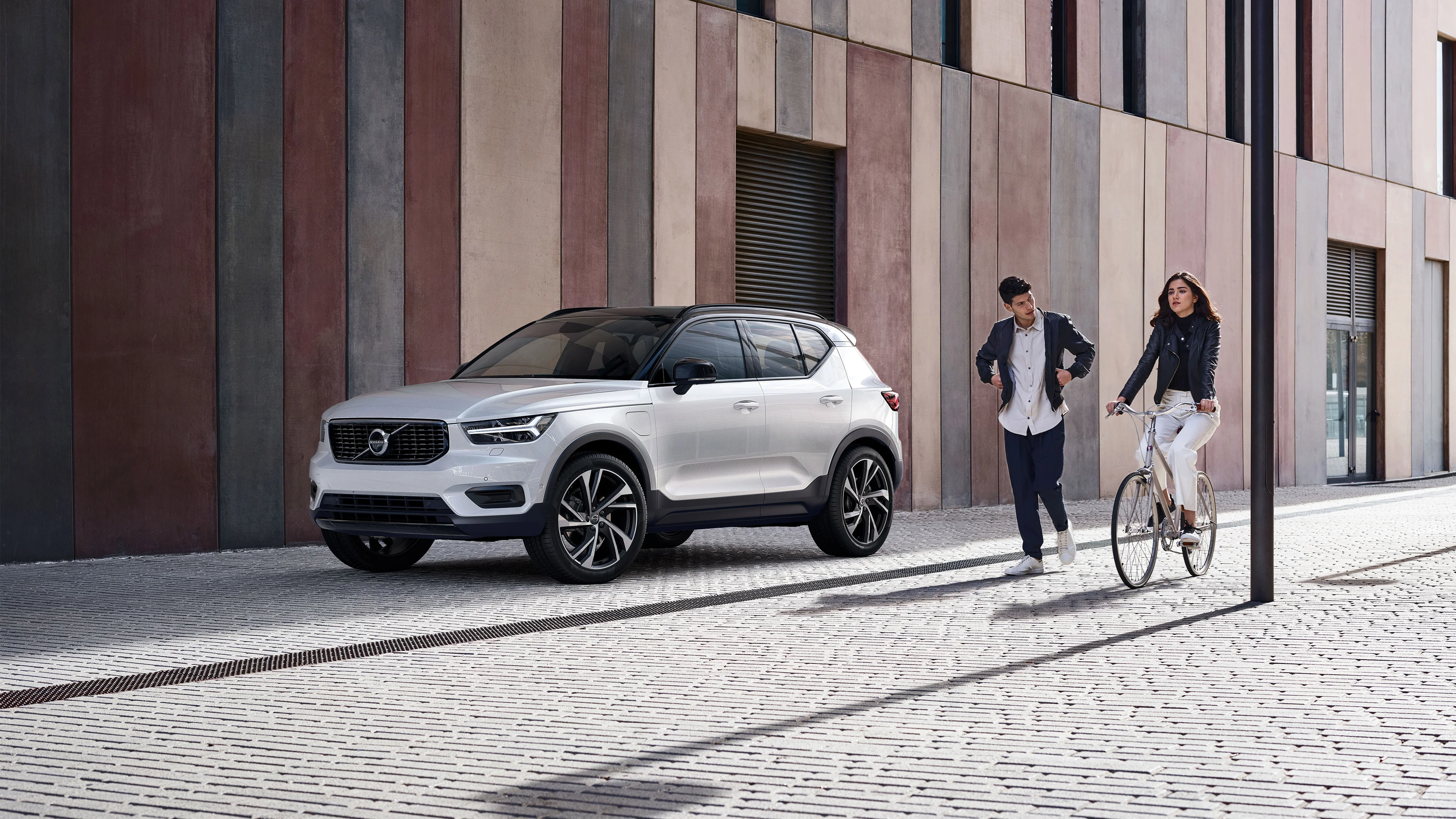Couple qui marche et a velo devant la voiture Volvo XC40