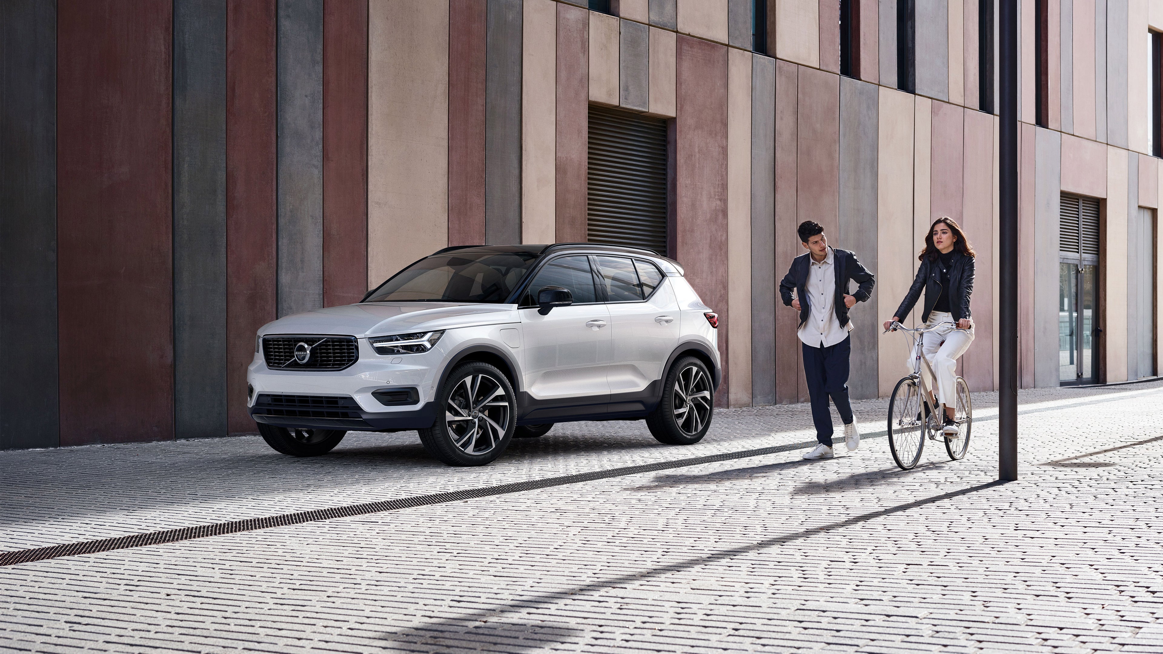 Couple qui marche et a velo devant la voiture Volvo XC40