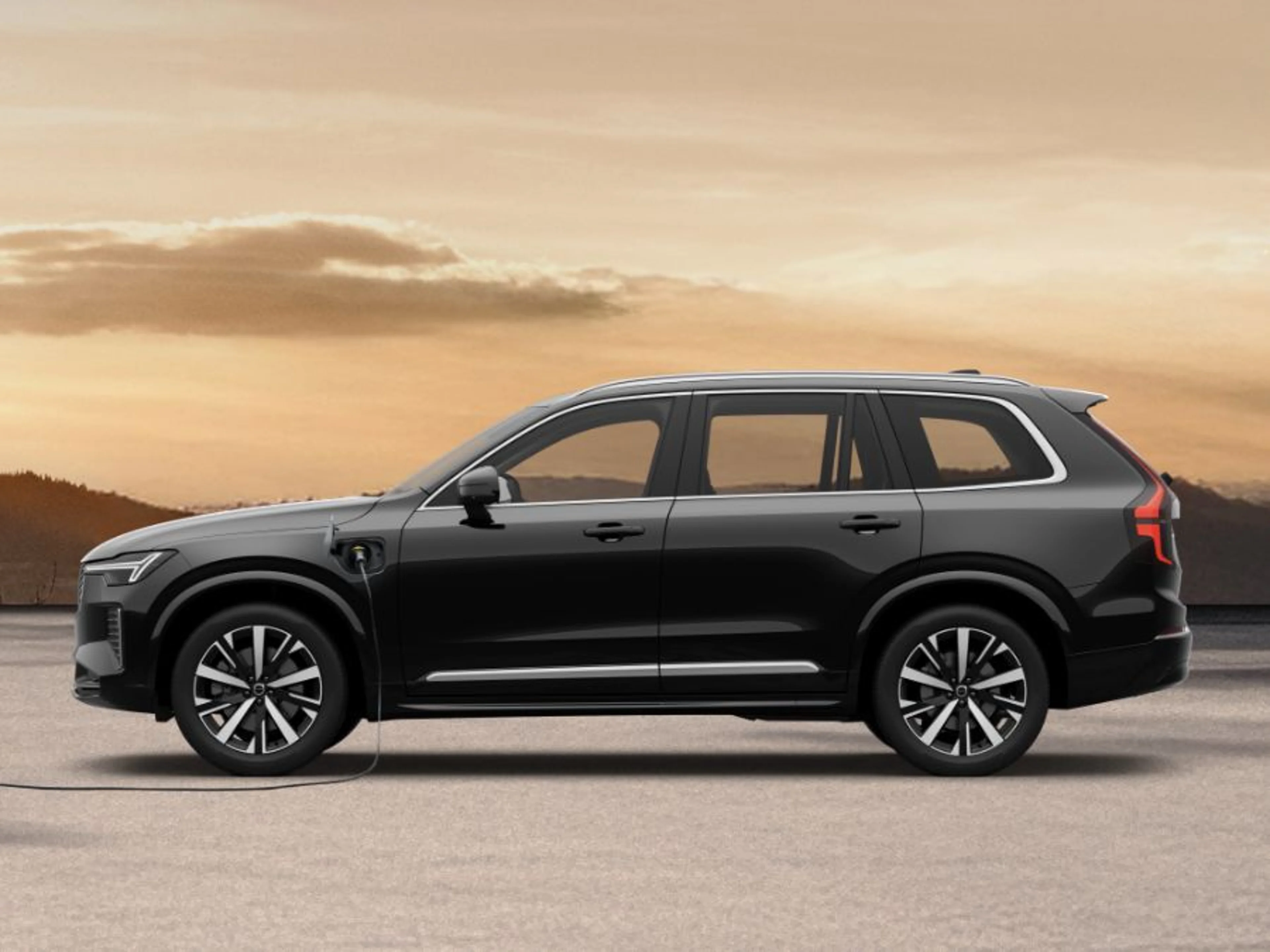 Volvo XC90 plug-in hybrid med polnjenjem ob sončnem zahodu.