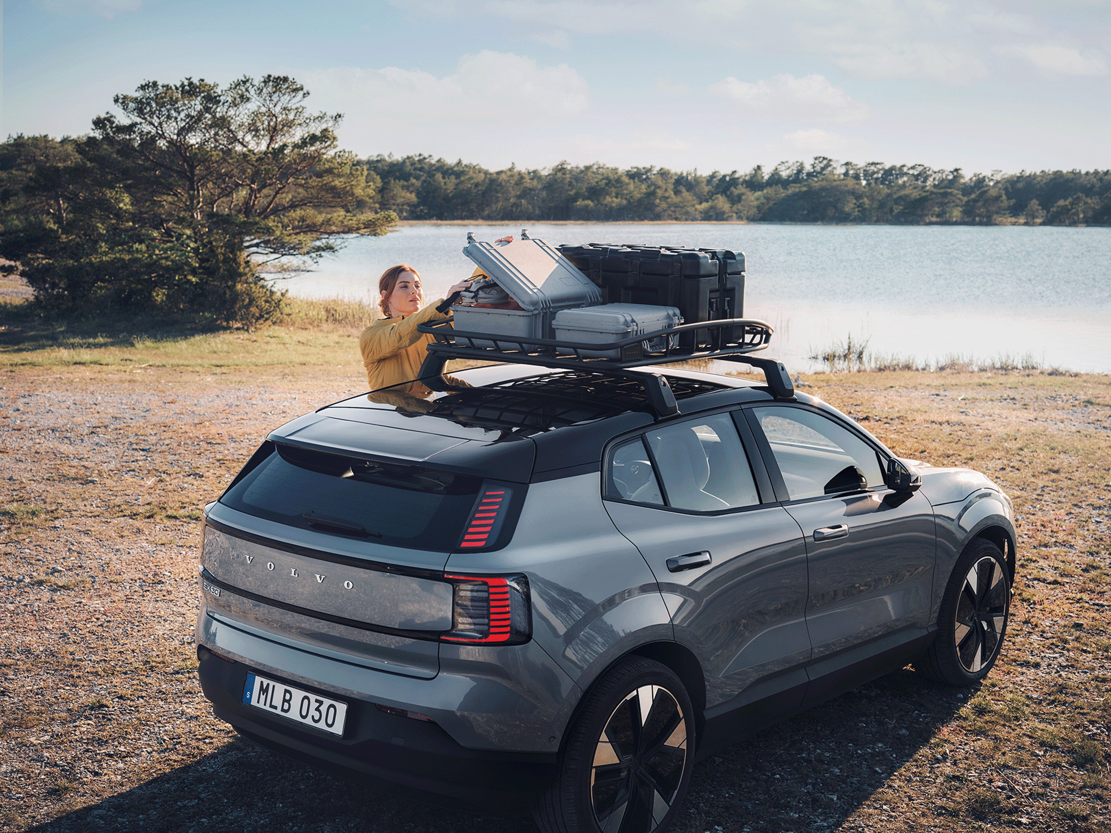 Eine Frau öffnet eine Volvo Dachbox auf einem Volvo EX30.
