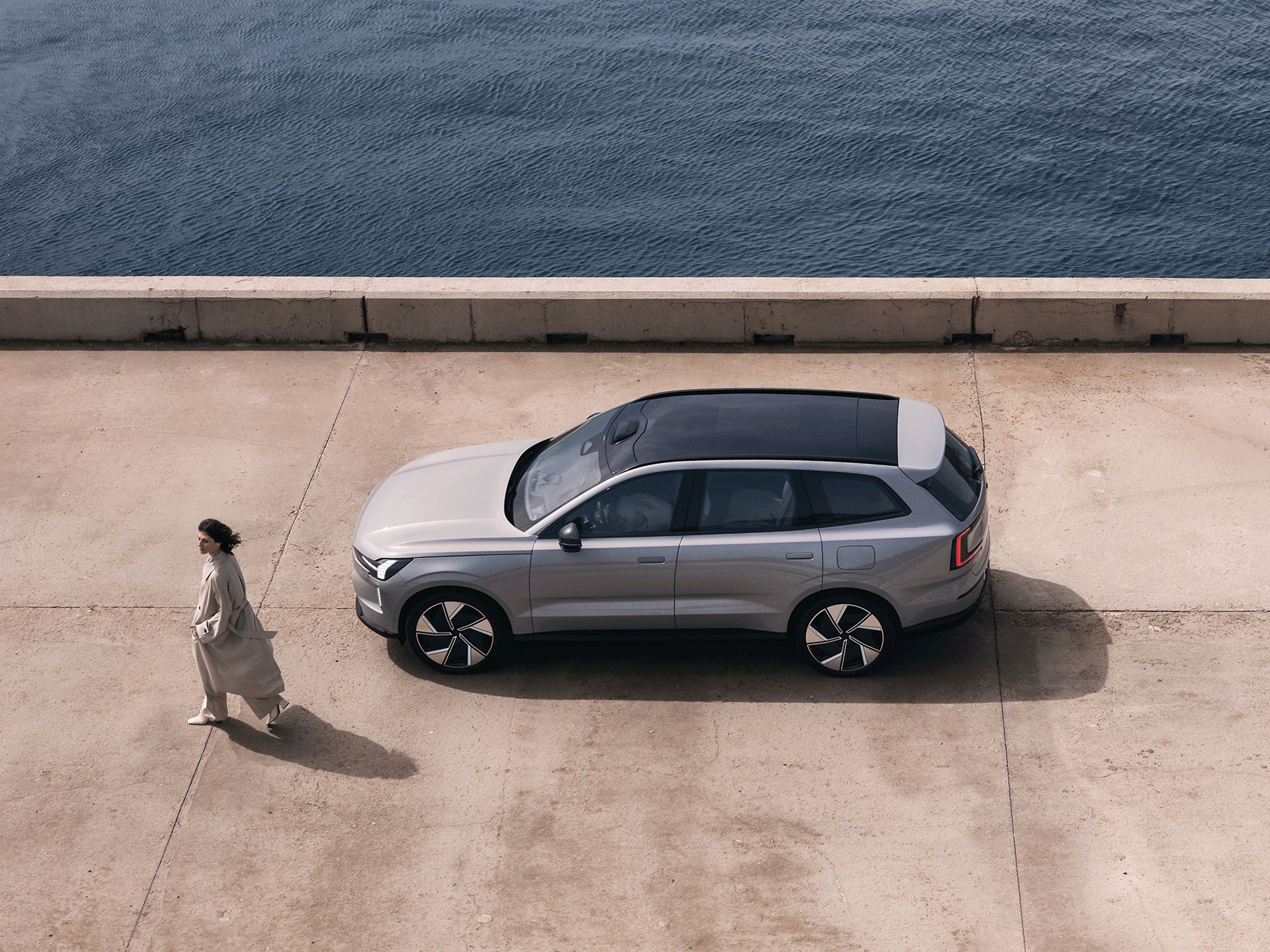 Eine Frau läuft neben einem Volvo EX90.