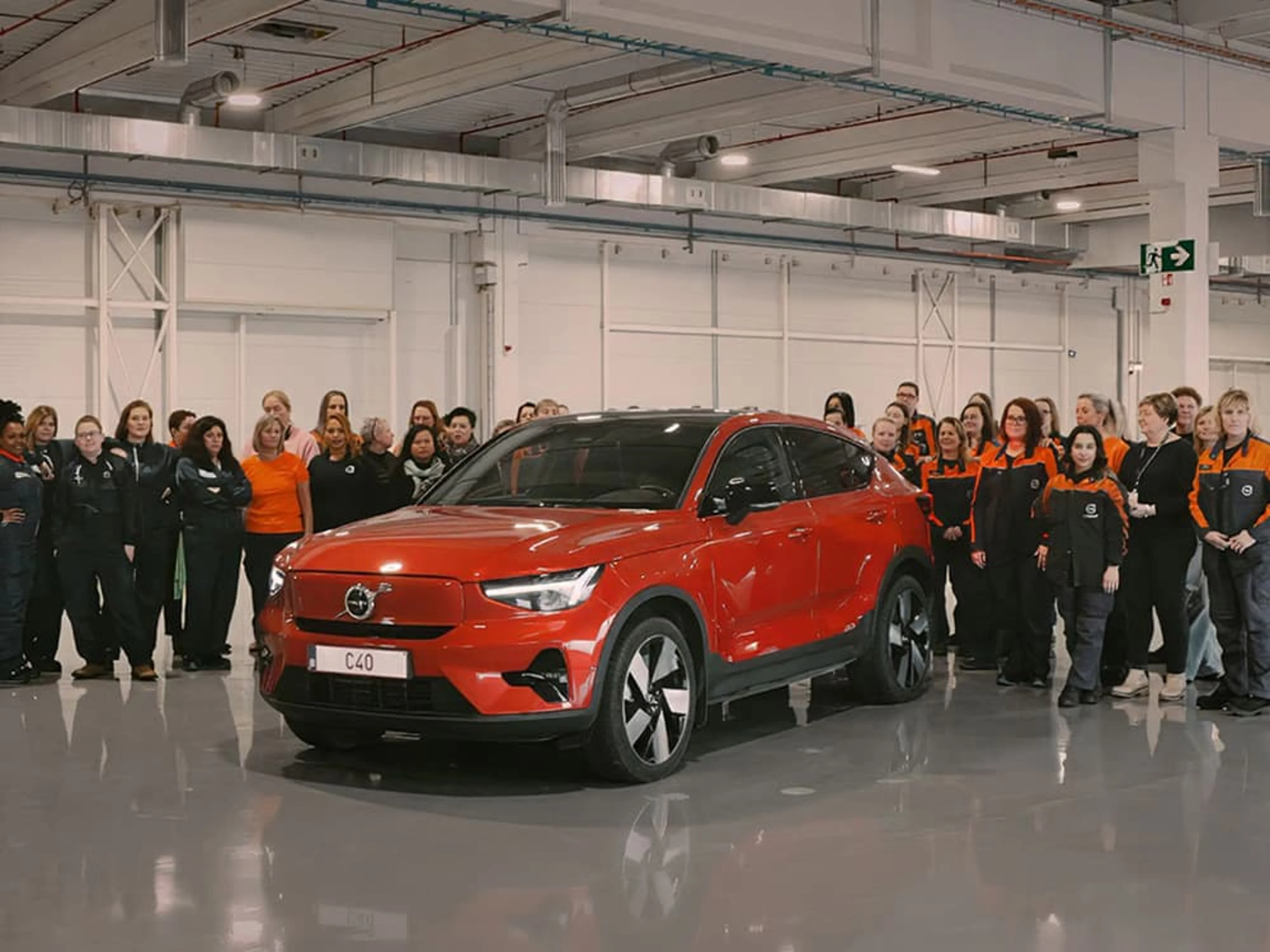 Toutes les employées de Volvo Car Gent se tiennent derrière une Volvo EC40 rouge dans l'usine.
