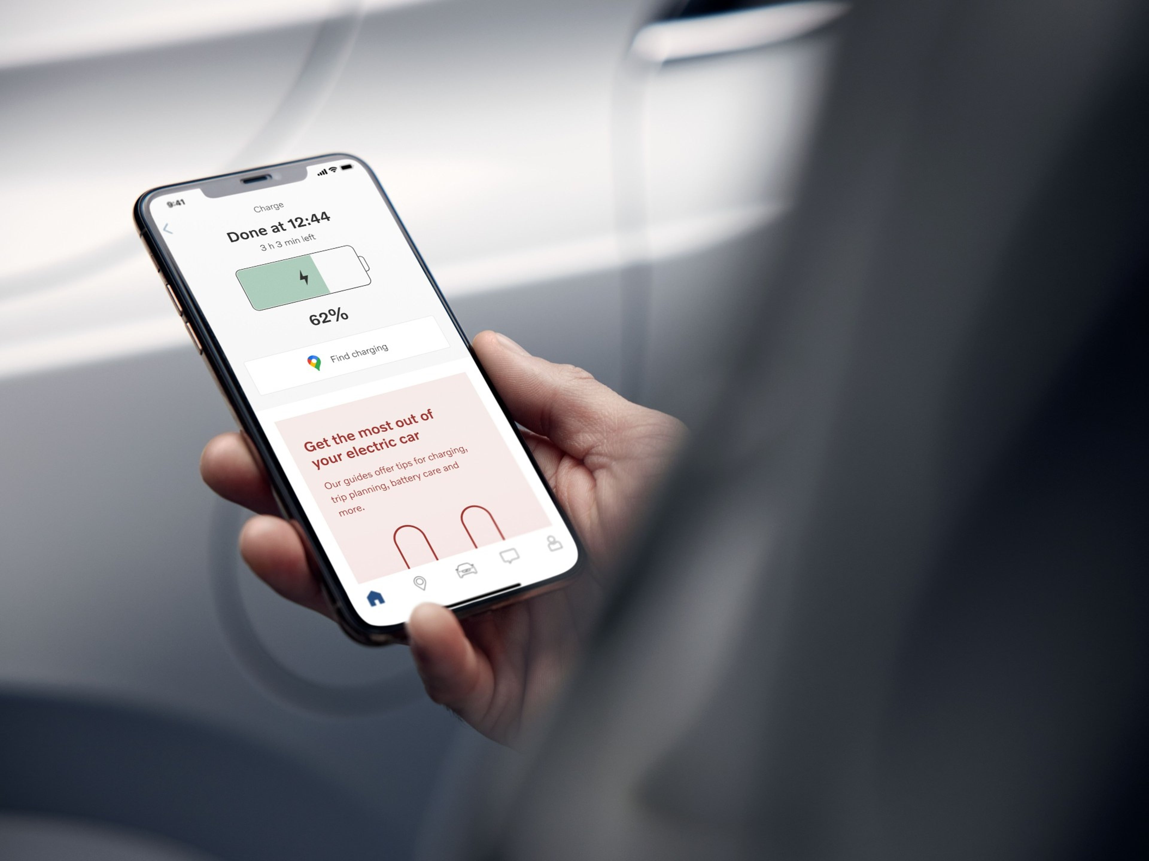 close de uma mão a segurar um telemóvel com a app volvo aberta, a verificar o carregamento da bateria