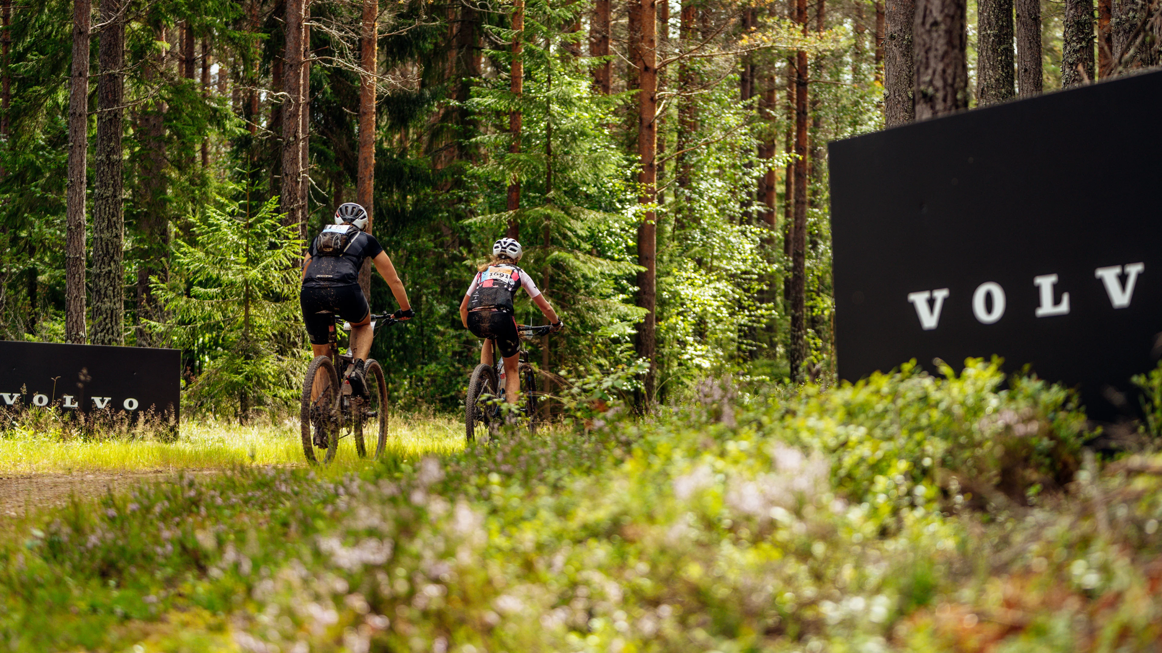 Två cyklister som tävlar i Cykelvasan i lummig skog