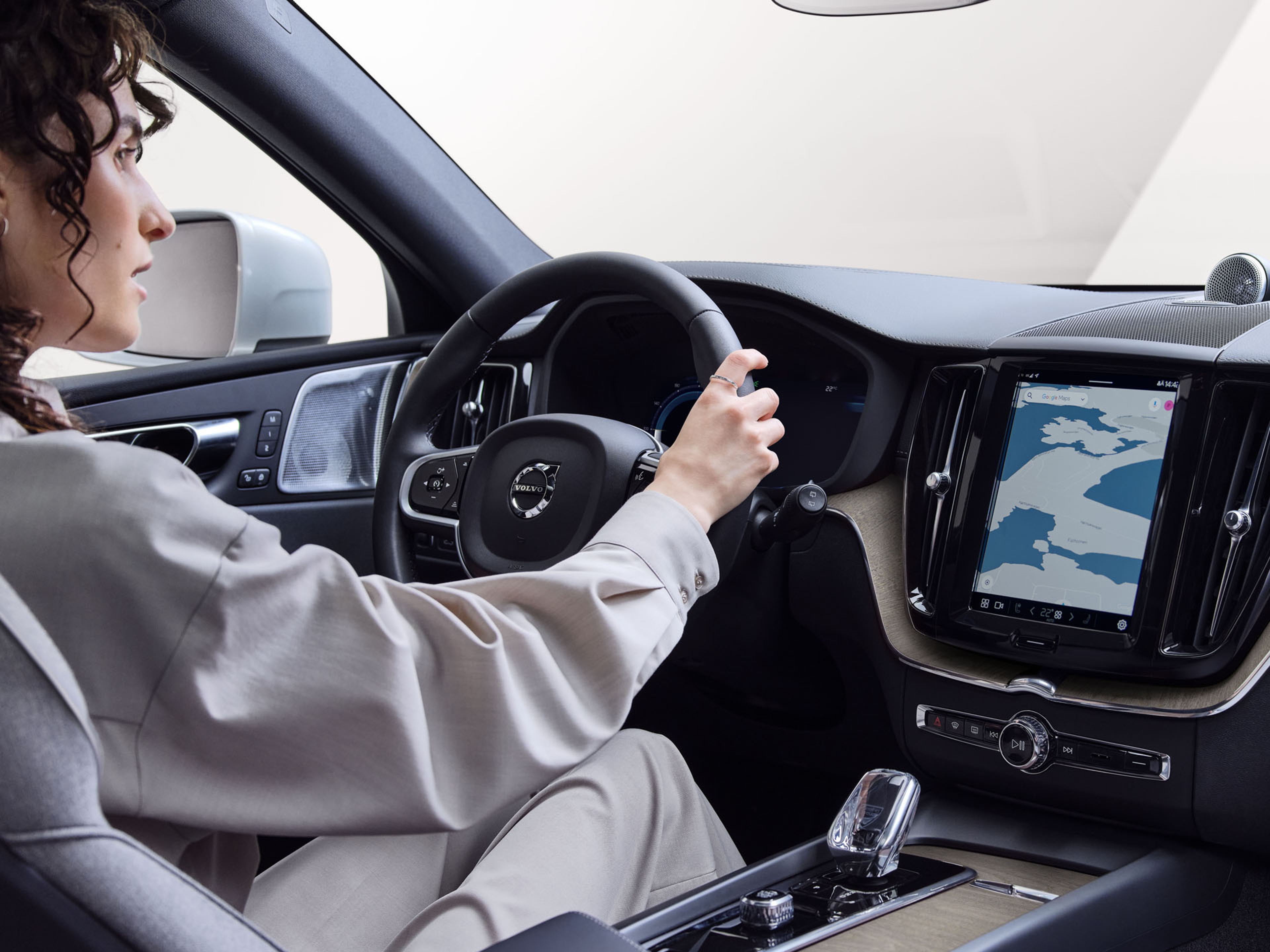 Una mujer conduciendo un vehículo Volvo y mirando al exterior